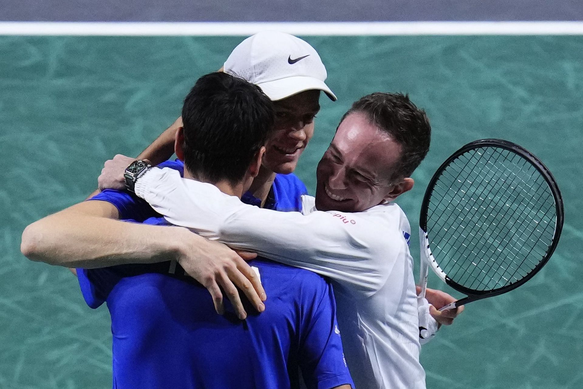 Captain of Team Italy Filippo Volandri (R) hugs Janik Sinner, centre, and Lorenzo Sonego