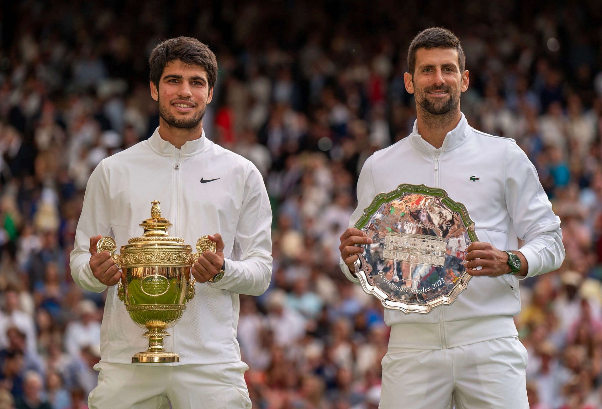 Carlos Alcaraz (L) and Novak Djokovic pose during the 2023 Wimbledon Championships trophy ceremony.