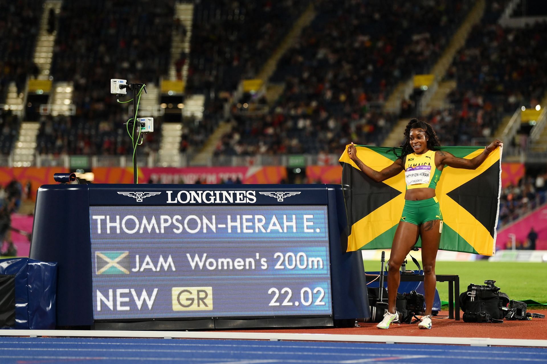Elaine Thompson-Herah of Team Jamaica celebrates a new Games Record next to the time board after winning the gold medal in the Women&#039;s 200m Final at the 2022 Commonwealth Games in Birmingham, England.