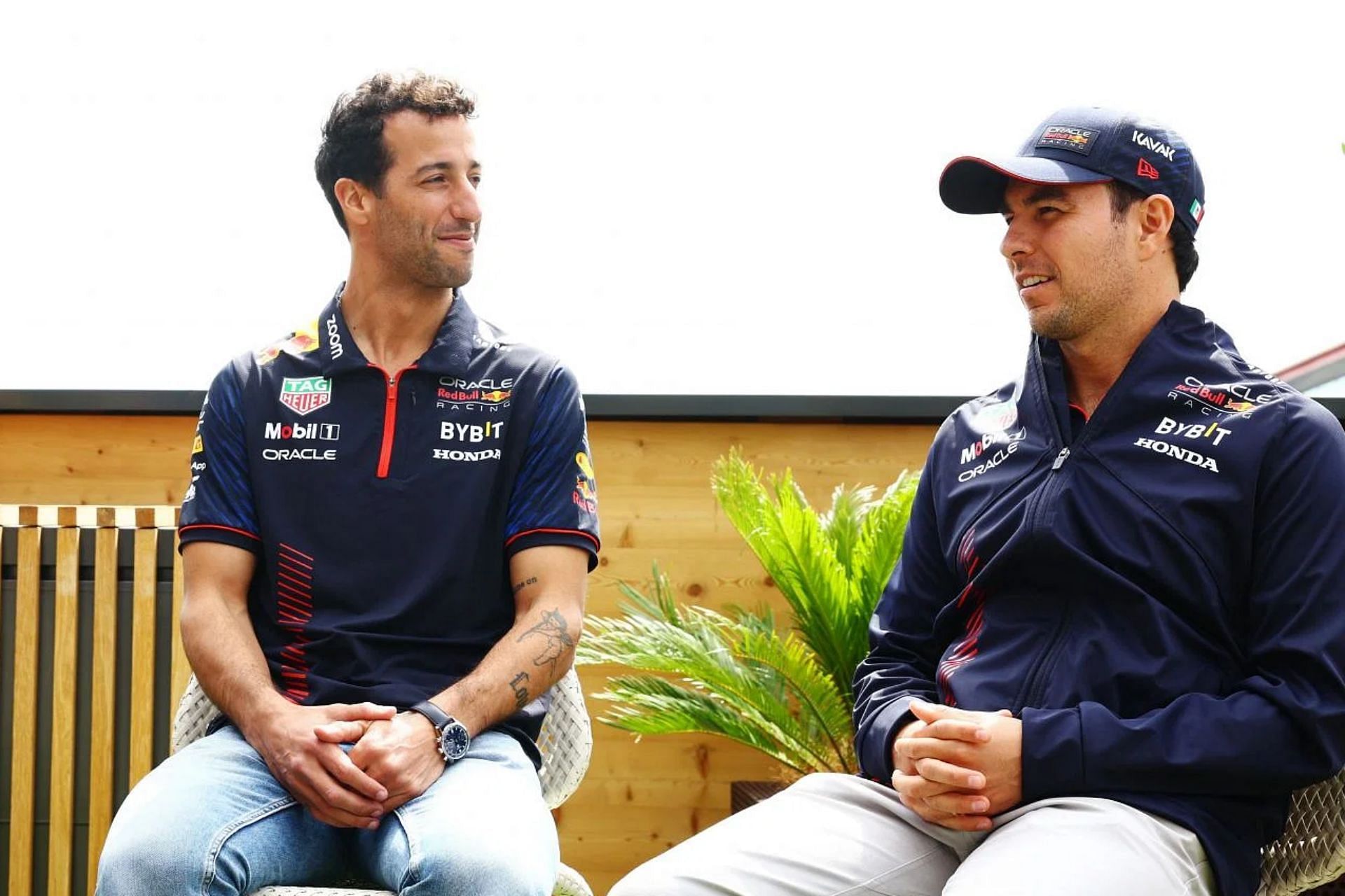 Daniel Ricciardo and Sergio Perez talk in the paddock during previews ahead of the 2023 F1 British Grand Prix. (Photo by Mark Thompson/Getty Images)