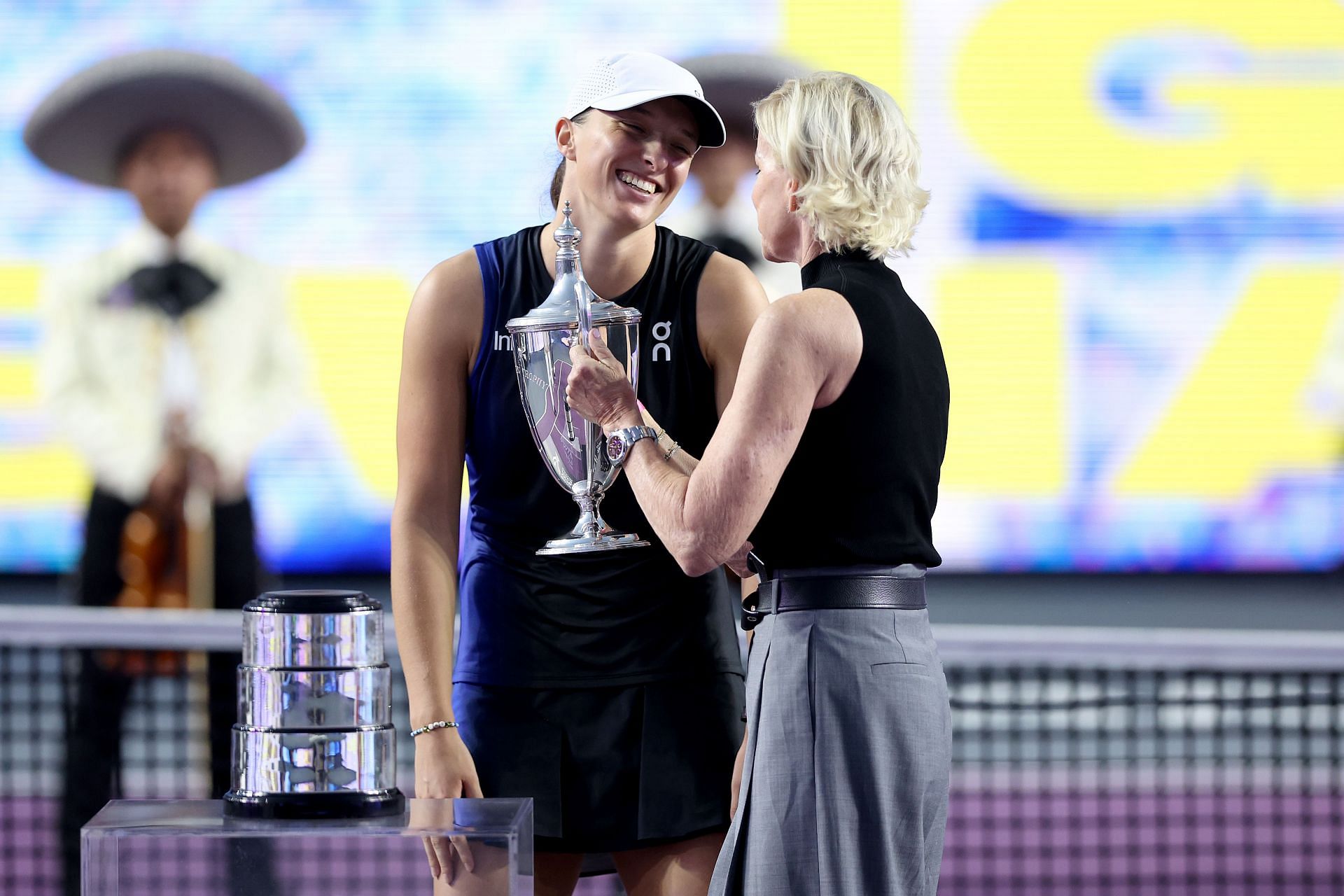 Iga Swiatek receives the Billie Jean King Trophy from Chris Evert