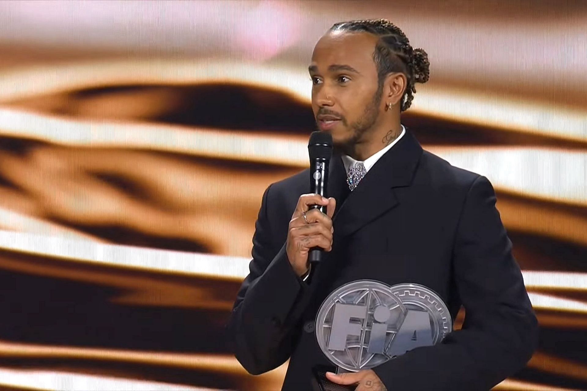 Lewis Hamilton receiving the FIA trophy for finishing third in the 2023 F1 season (Image via YouTube/FORMULA 1)