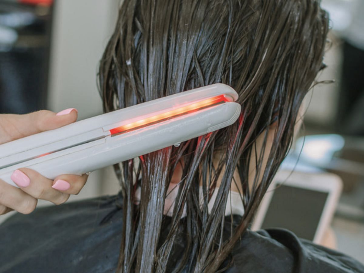 Using a hair straightener on wet hair (Image via Pixabay)