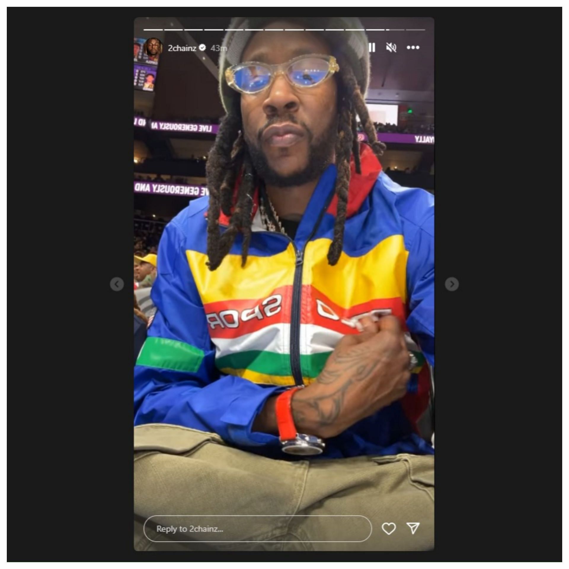 2 Chainz showing off his jacket while sitting courtside