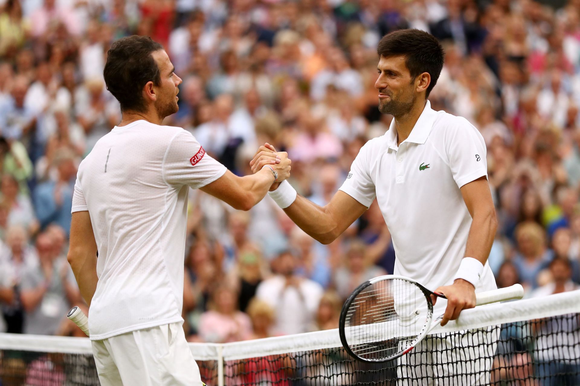 Adrian Mannarino (L) shakes hands with Novak Djokovic