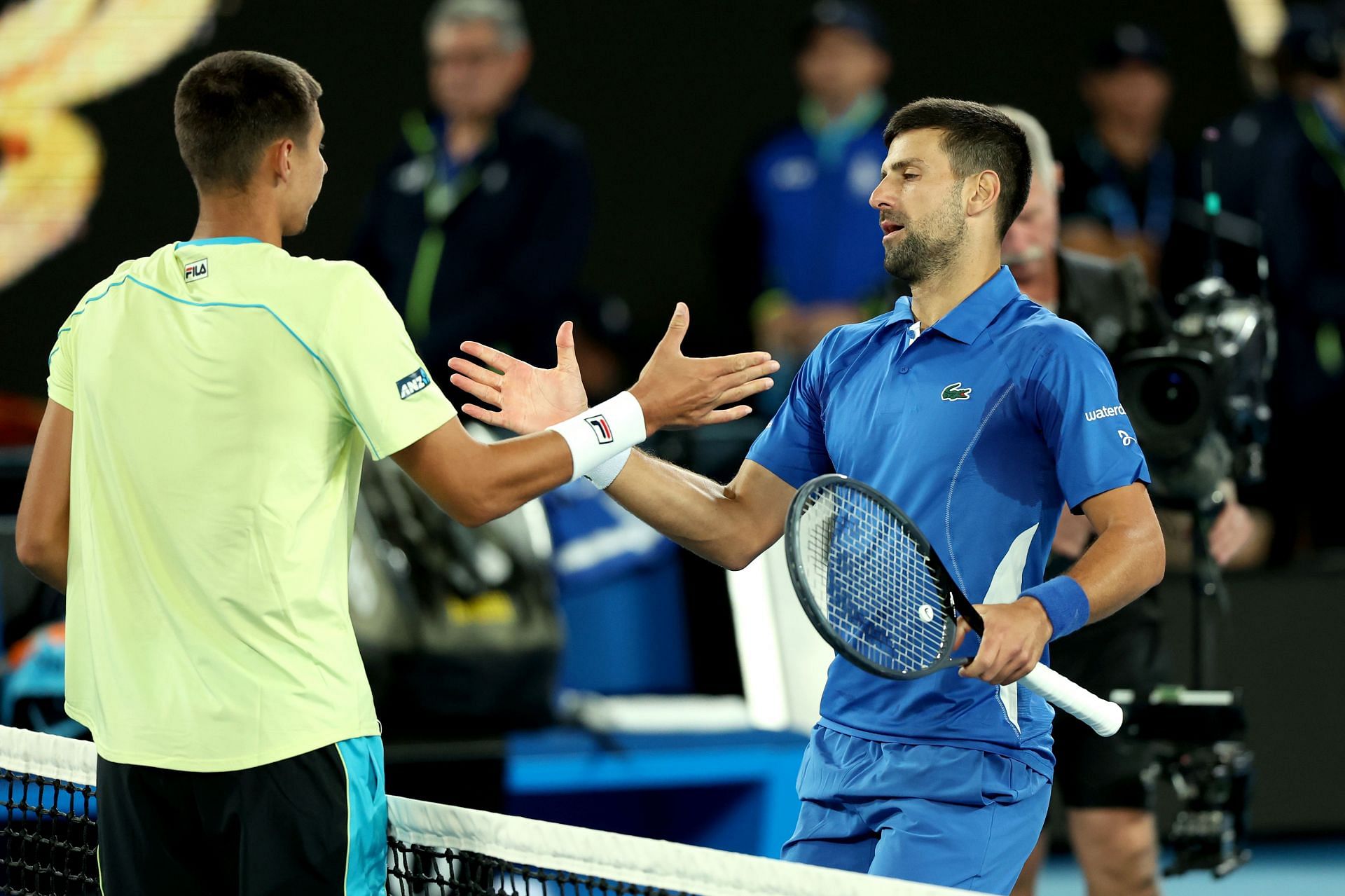 Novak Djokovic and Alexei Popyrin greet each other at the net following their match.