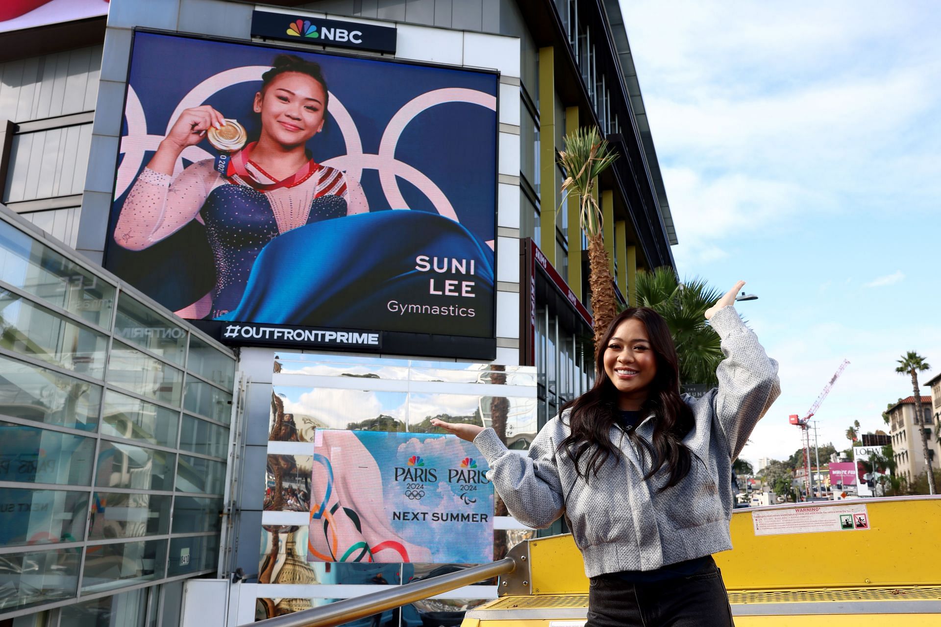 Suni Lee poses with her sign on the Sunset Strip during the Team USA Road to Paris Bus in Los Angeles, California.