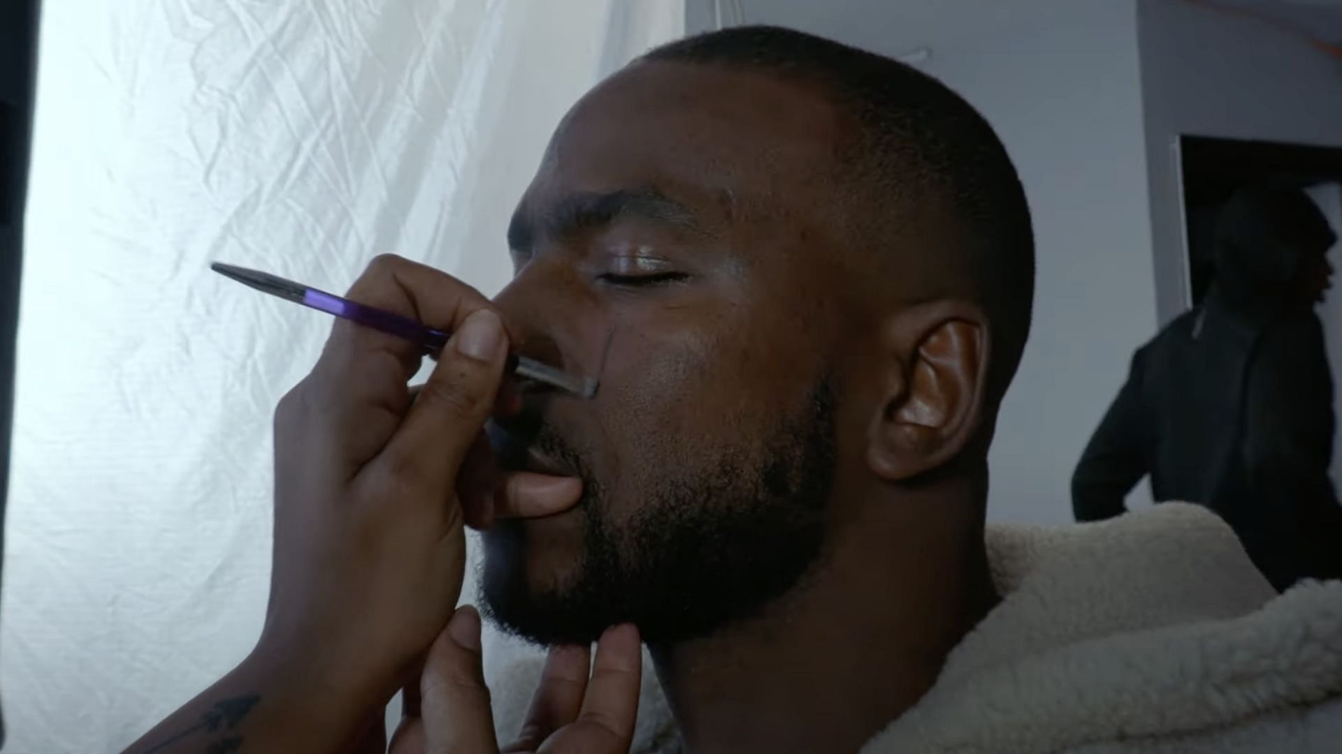 Skepta getting his makeup done for Tribal Mark (Image via YouTube/@SKEPTAOFFICIAL)