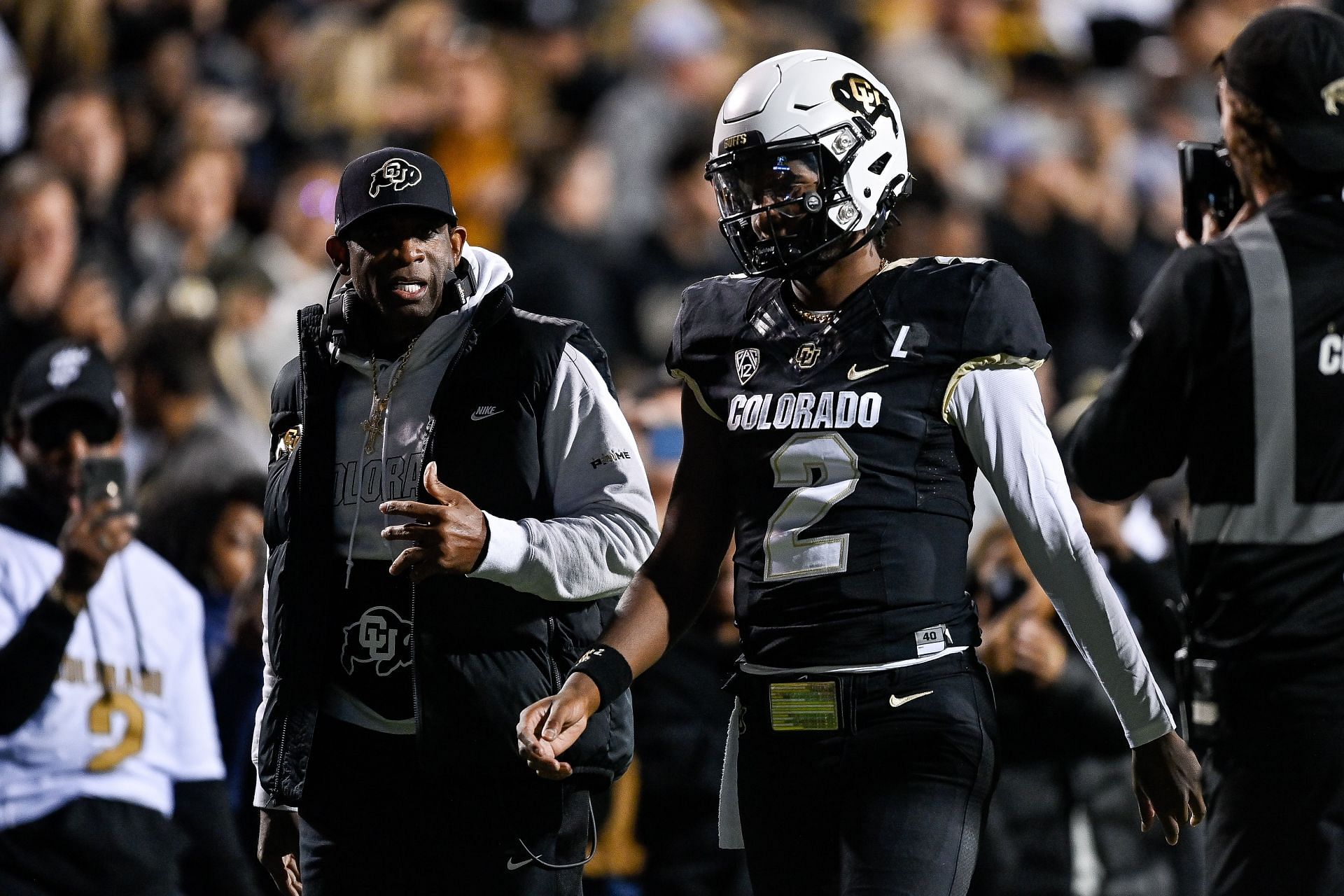 Head coach Deion Sanders of the Colorado Buffaloes (L) has a word with Shedeur Sanders #2