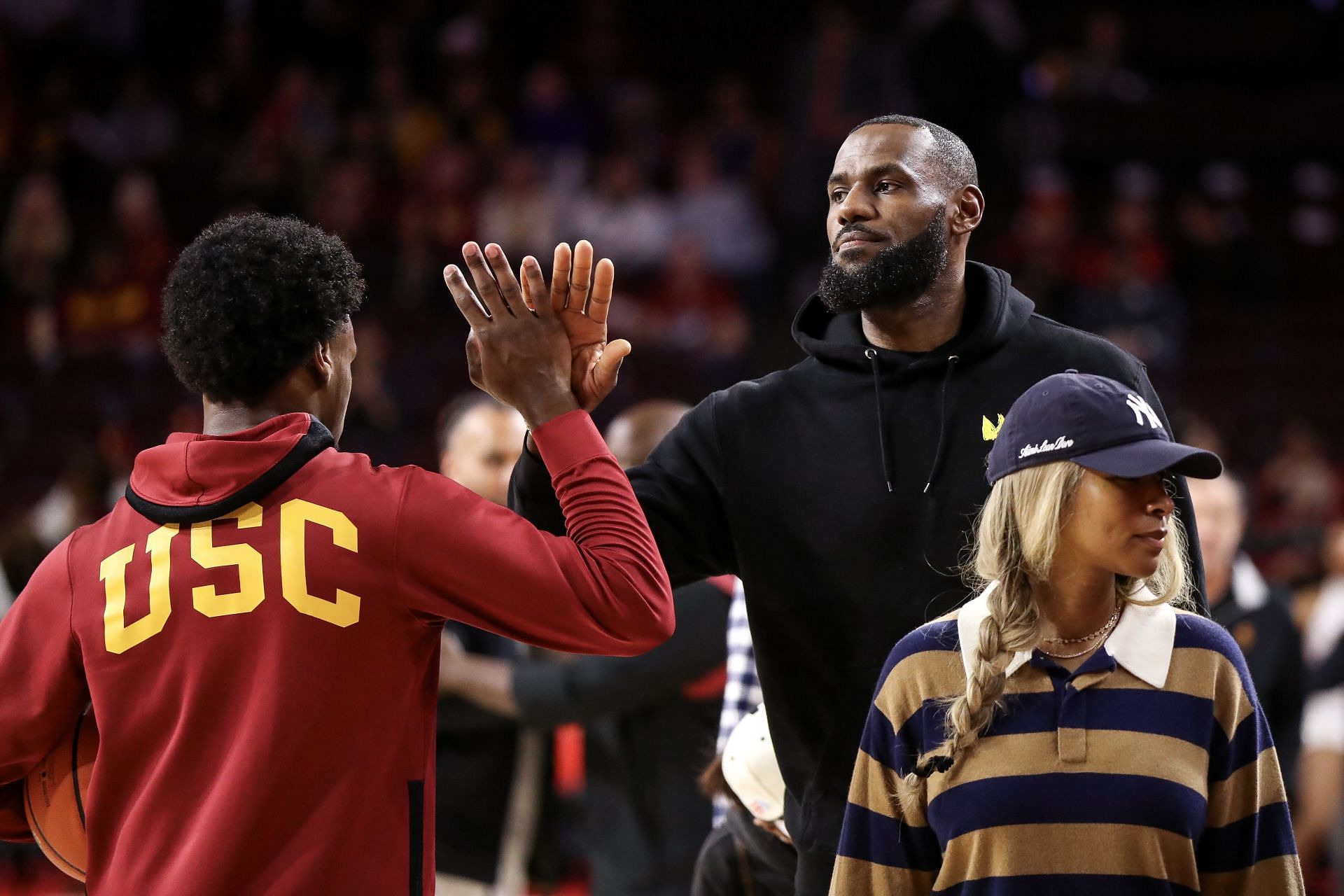 Bronny James of the USC Trojans greets his dad, LeBron James of the LA Lakers, before a game against the Stanford Cardinal.