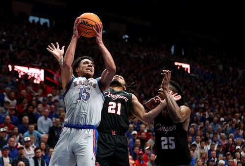 Kevin McCullar Jr. #15 of the Kansas Jayhawks shoots over Emanuel Sharp #21 and Joseph Tugler #25 of the Houston Cougars during the first half of the game at Allen Fieldhouse.