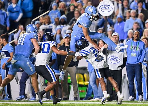 Drake Maye hurdling a defender