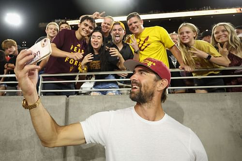 Michael Phelps takes a selfie with fans during the first half of the NCAAF game between the Arizona State Sun Devils and the USC Trojans at Mountain America Stadium on September 23, 2023, in Tempe, Arizona. (Photo by Christian Petersen/Getty Images)