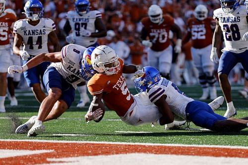 Adonai Mitchell #5 of the Texas Longhorns is tackled short of the goal line by O.J. Burroughs #5 of the Kansas Jayhawks and Austin Booker #9