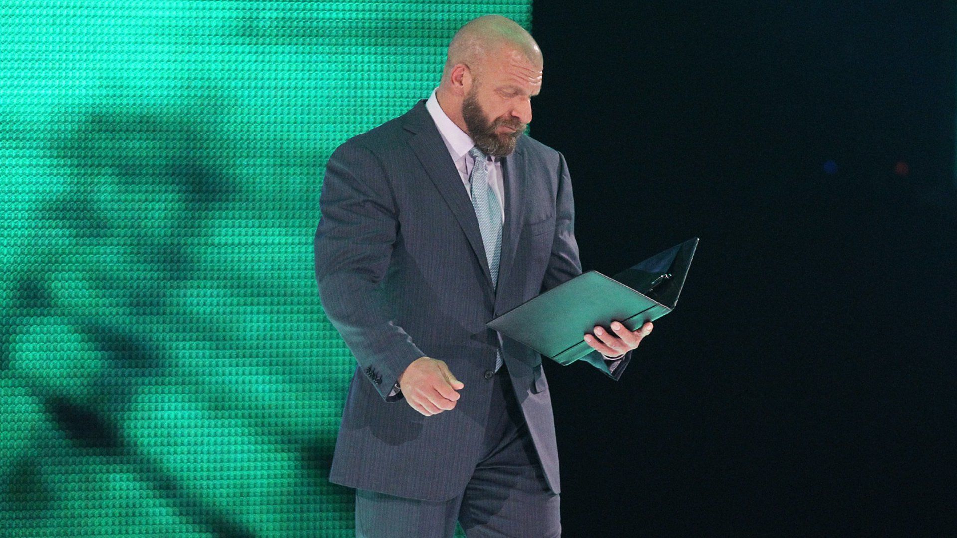WWE Chief Content Officer Triple H looks over a contract
