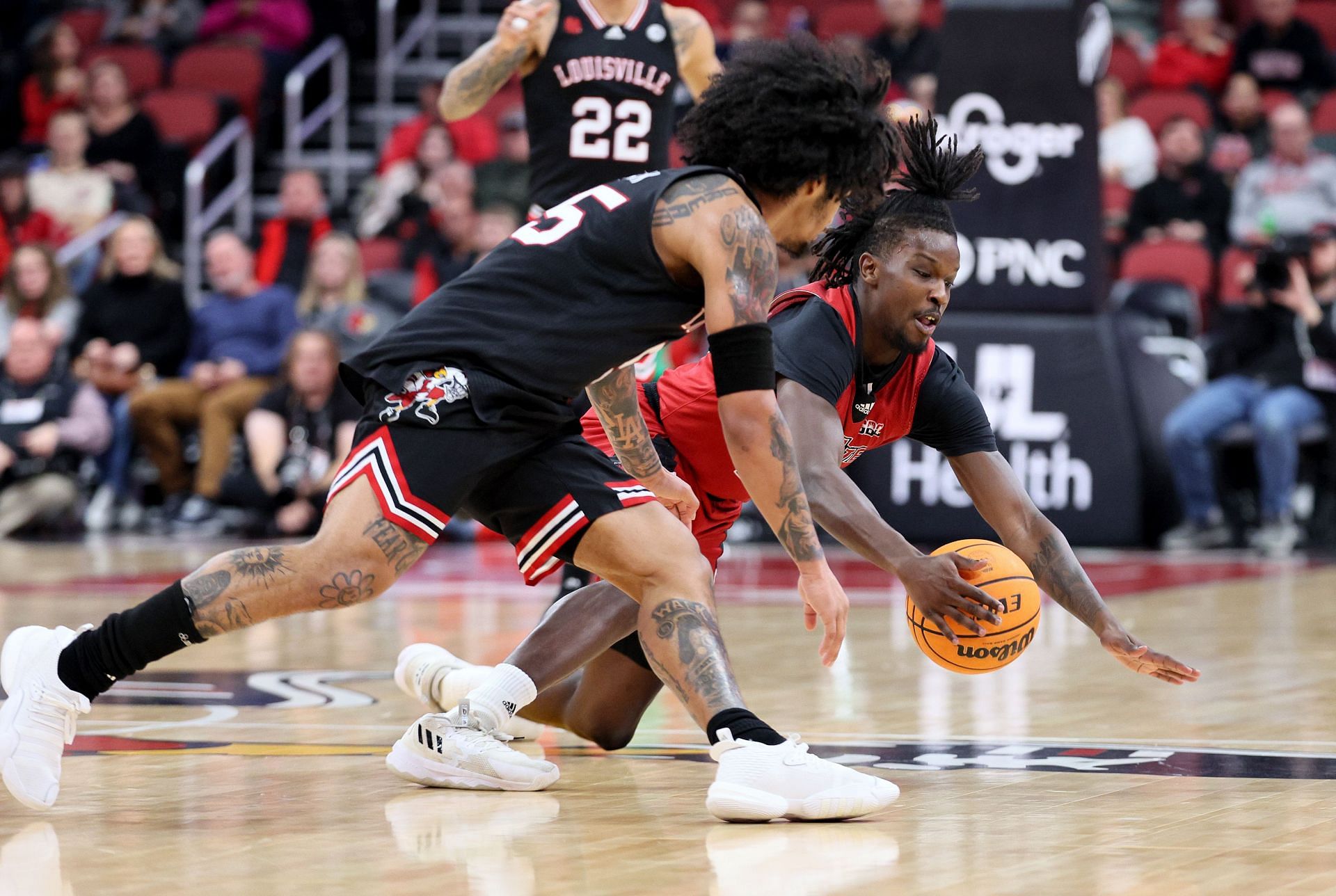 Julian Lual #23 of the Arkansas State Red Wolves and Skyy Clark #55 of the Louisville Cardinals battle for a loose ball.