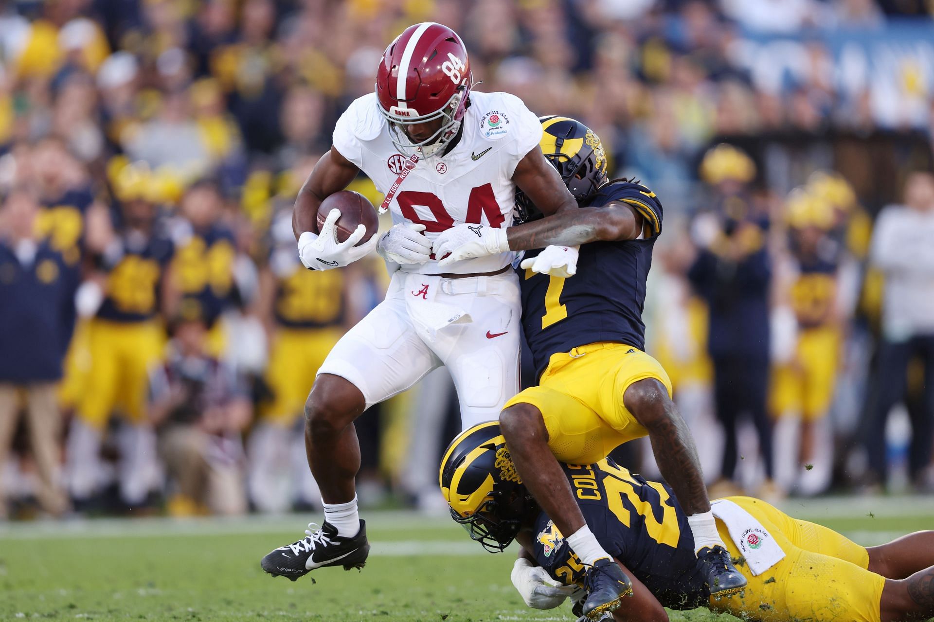 Amari Niblack #84 of the Alabama Crimson Tide runs with the ball while being tackled by Junior Colson #25 and Makari Paige #7 of the Michigan Wolverines