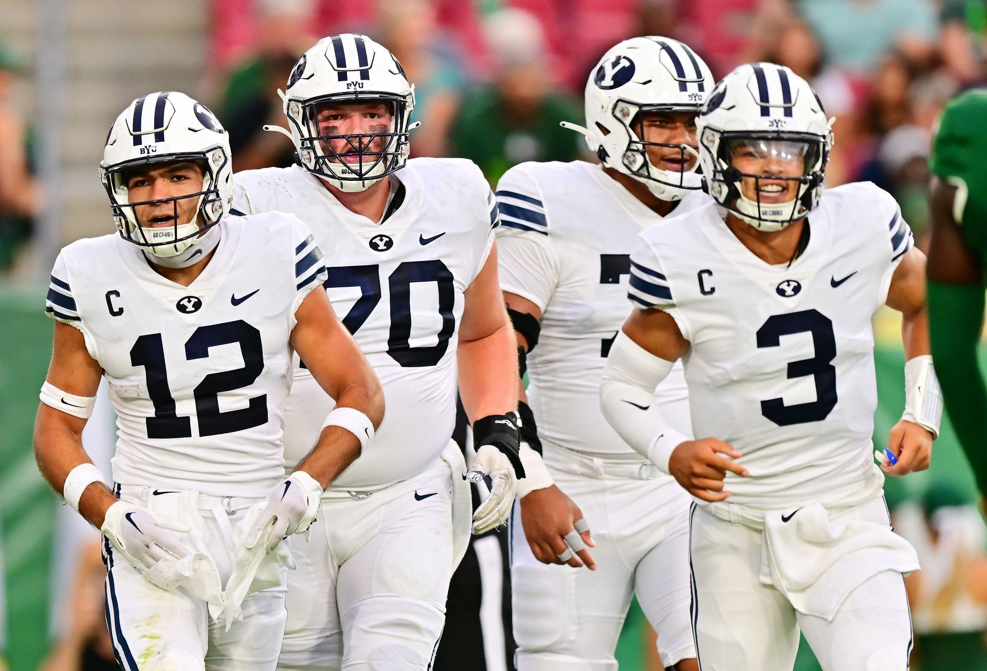 Puka Nacua #12, Connor Pay #70, Kingsley Suamataia #78, and Jaren Hall #3 of the Brigham Young Cougars celebrate after a touchdown 