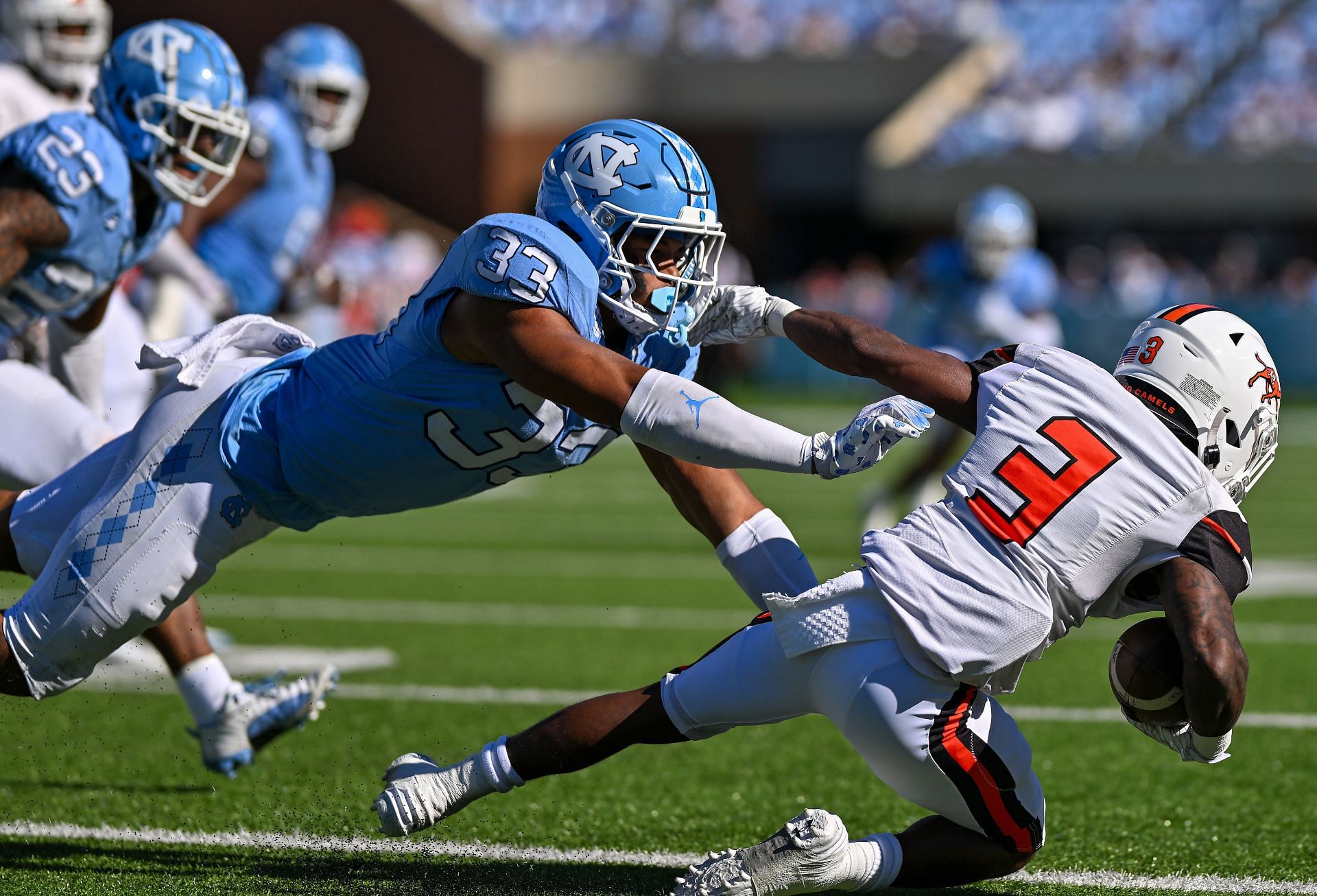 Cedric Gray #33 of the North Carolina Tar Heels tackles Tai Goode #3 of the Campbell Fighting Camels