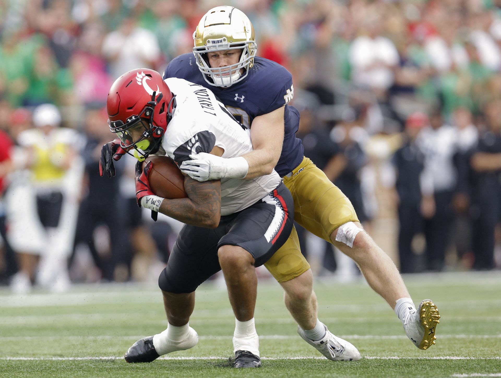 Leonard Taylor #11 of the Cincinnati Bearcats runs the ball after a catch as J.D. Bertrand #27 of the Notre Dame Fighting Irish hangs on for the tackle