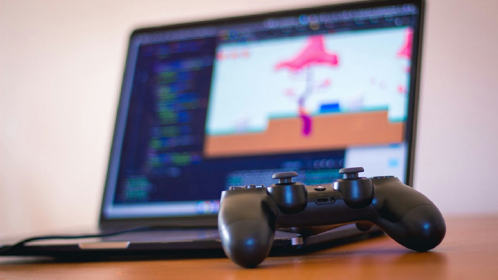 PS4 controller and a laptop (Image via Orva Studio/Unsplash)