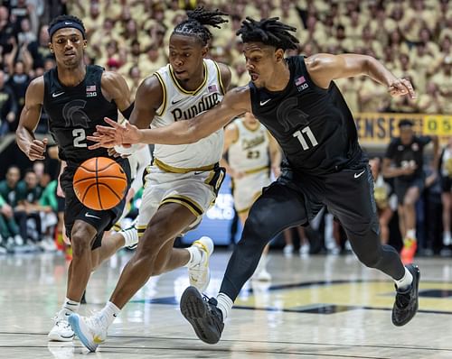 Lance Jones #55 of the Purdue Boilermakers and A.J. Hoggard #11 of the Michigan State Spartans reach for the ball during the second half .