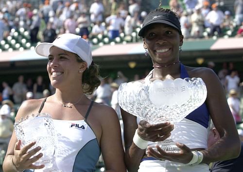 Venus Williams (R) holds the Miami Open 2001 women's singles trophy beside runner-up Jennifer Capriati.