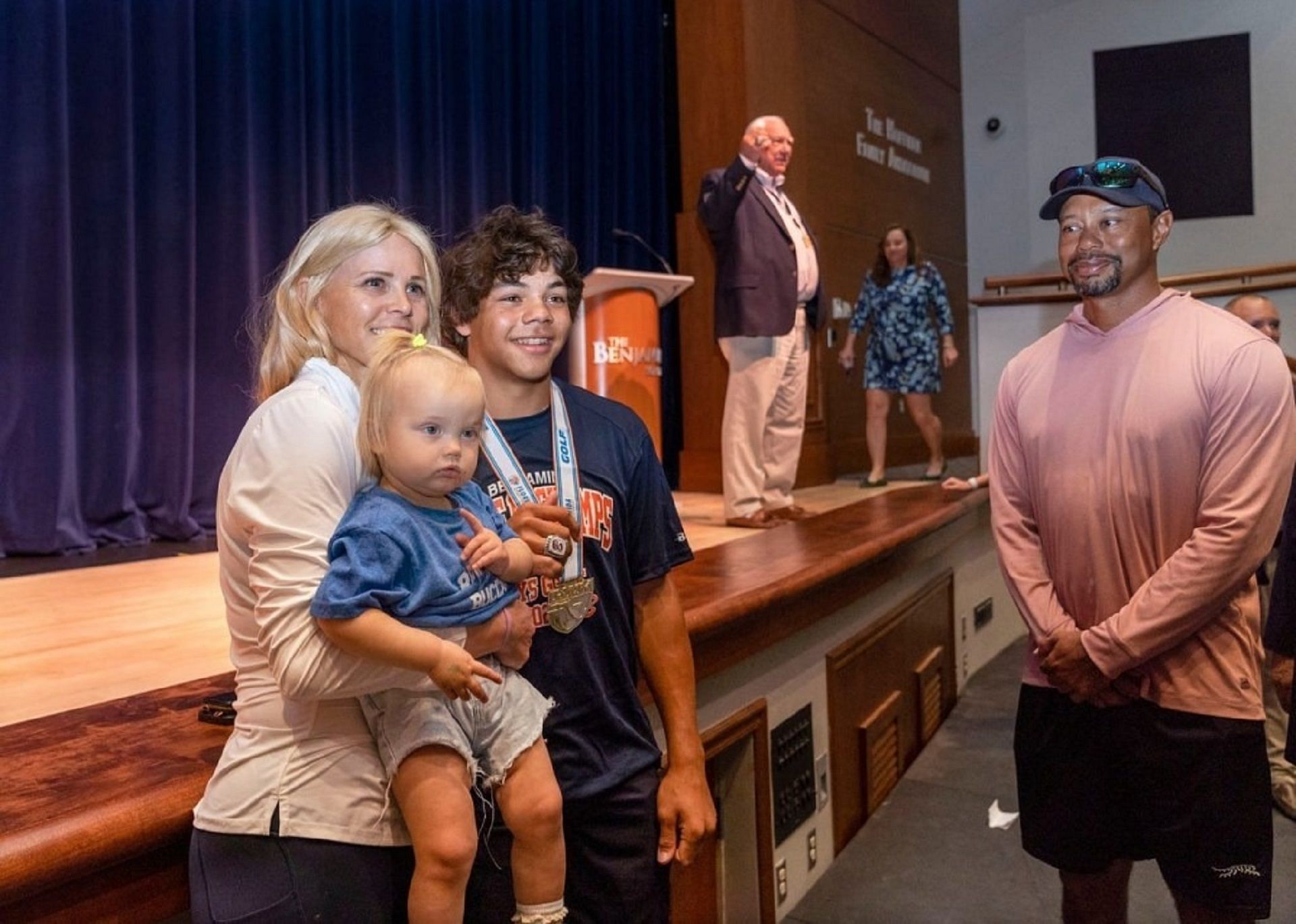 Charlie Woods poses with his mother Elin Nordegren, while Tiger Woods looks during the ring presentation ceremony at the Benjamin School in Florida for being state champions.