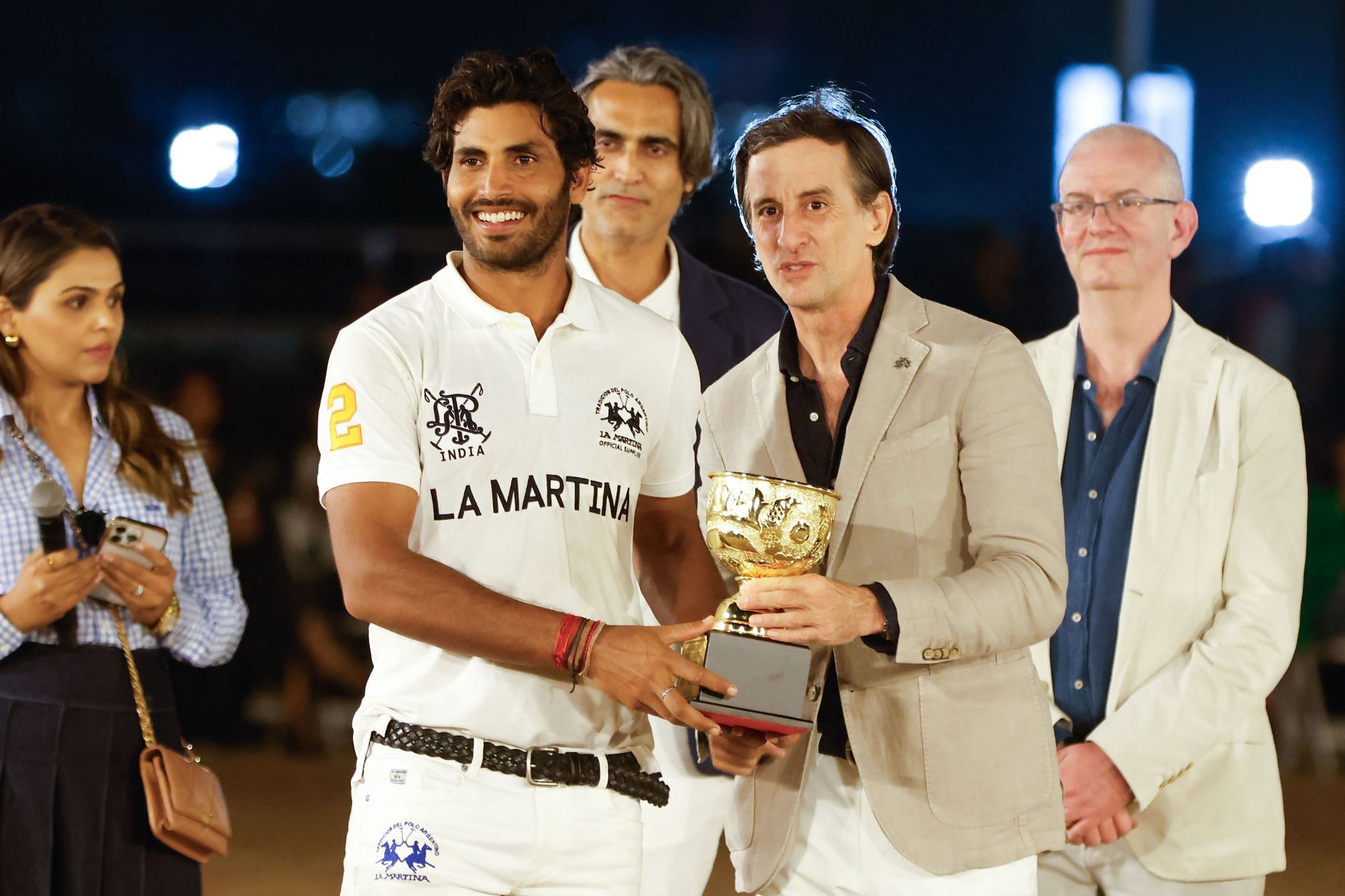 Naveen Singh (second from left) receives a trophy after the exhibition match.