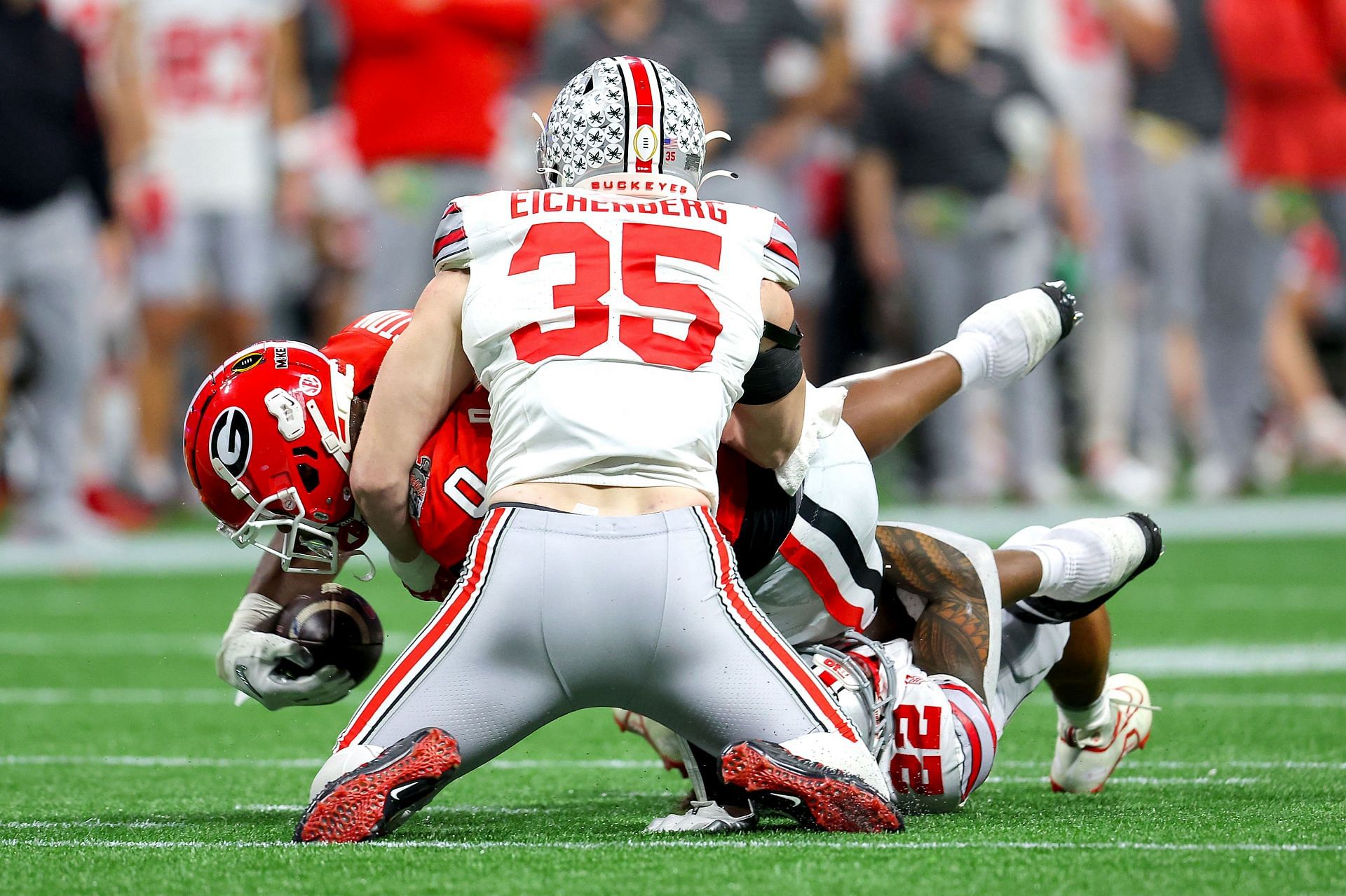 Darnell Washington #0 of the Georgia Bulldogs is tackled by Tommy Eichenberg #35 and Steele Chambers #22 of the Ohio State Buckeyes