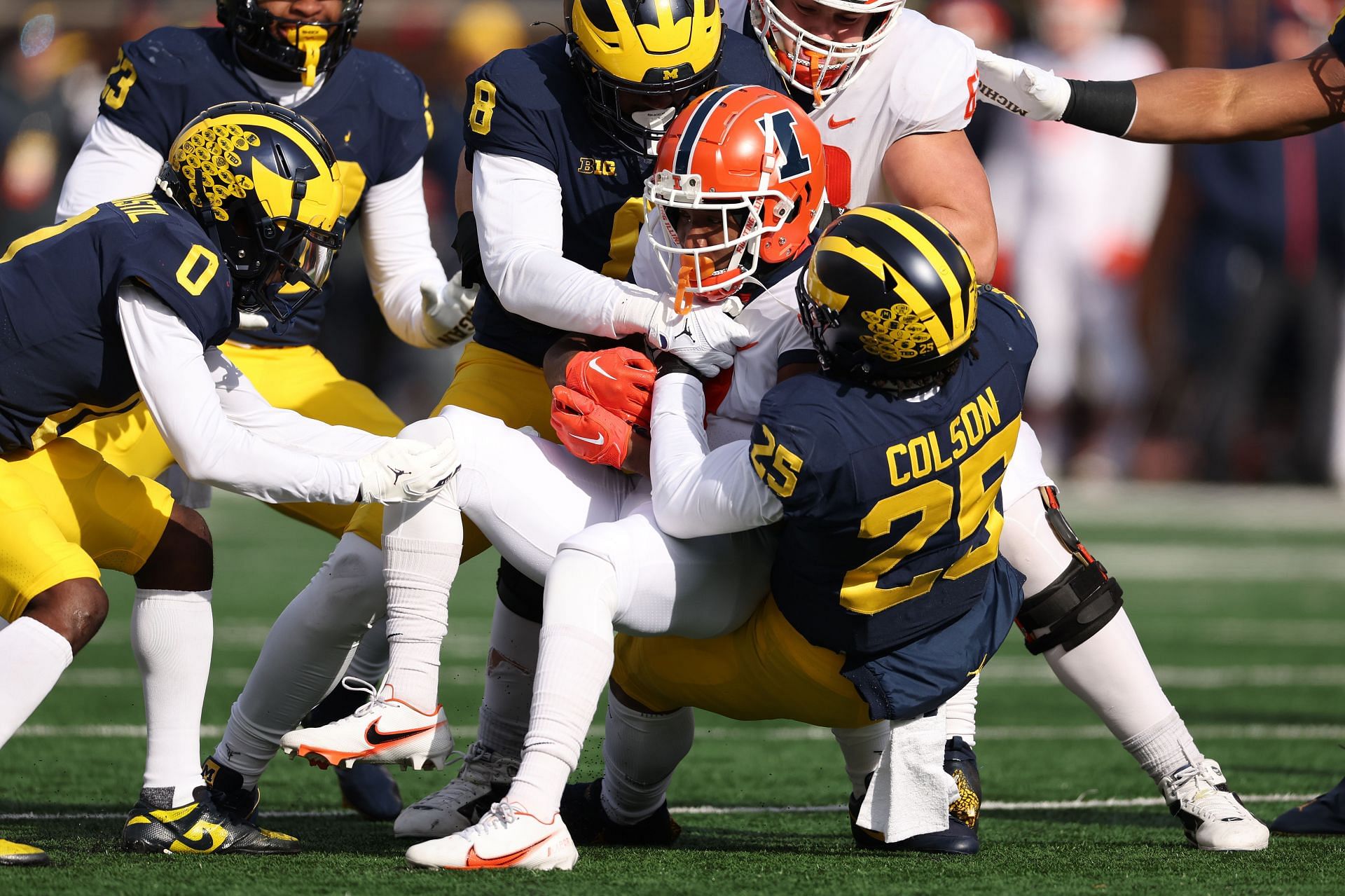 Isaiah Williams #1 of the Illinois Fighting Illini is tackled by Junior Colson #25 and Derrick Moore #8 of the Michigan Wolverines
