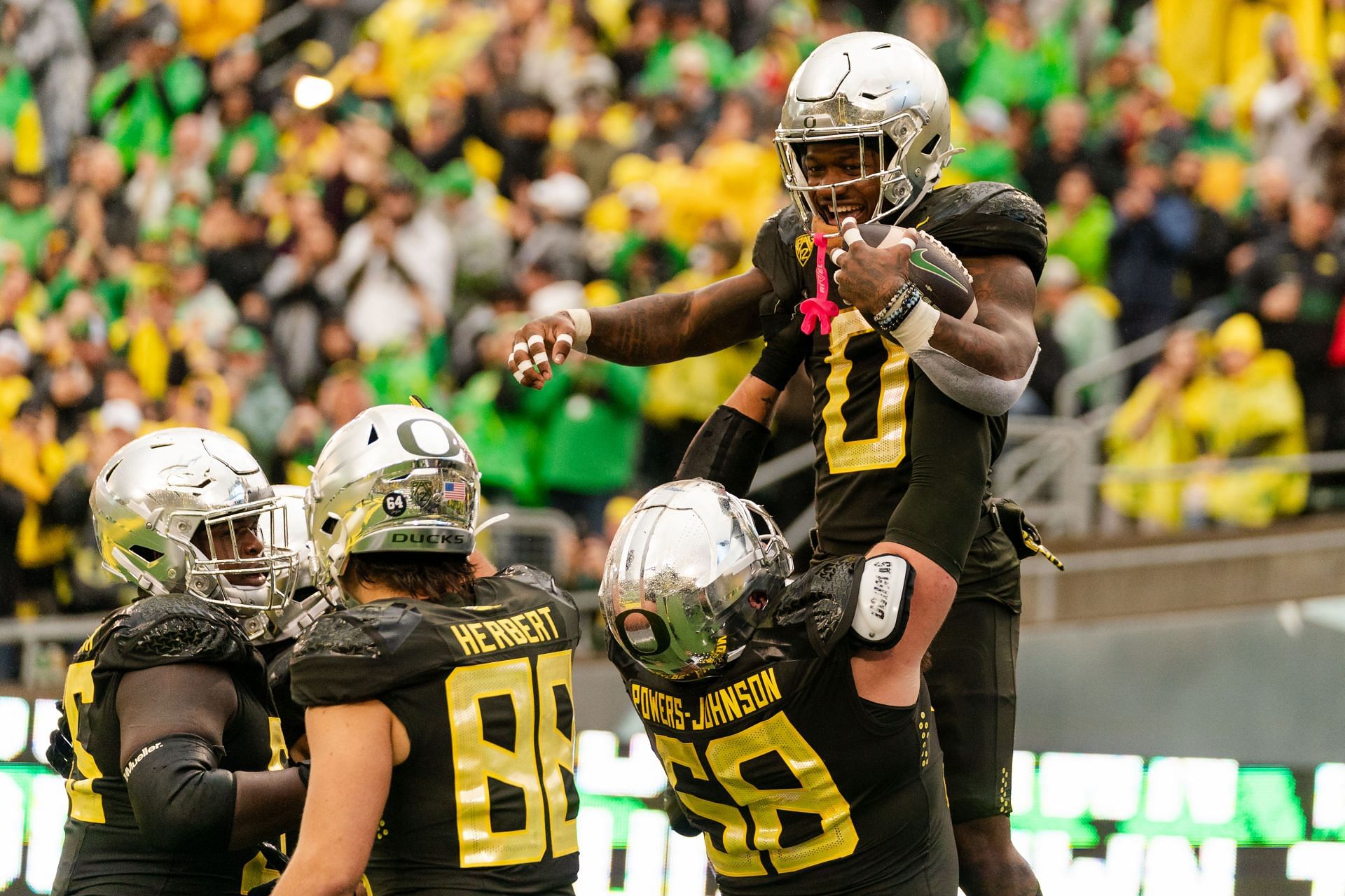 Jackson Powers-Johnson #58 of the Oregon Ducks lifts up Bucky Irving #0 after his touchdown during the second half of the game against the California Golden Bears