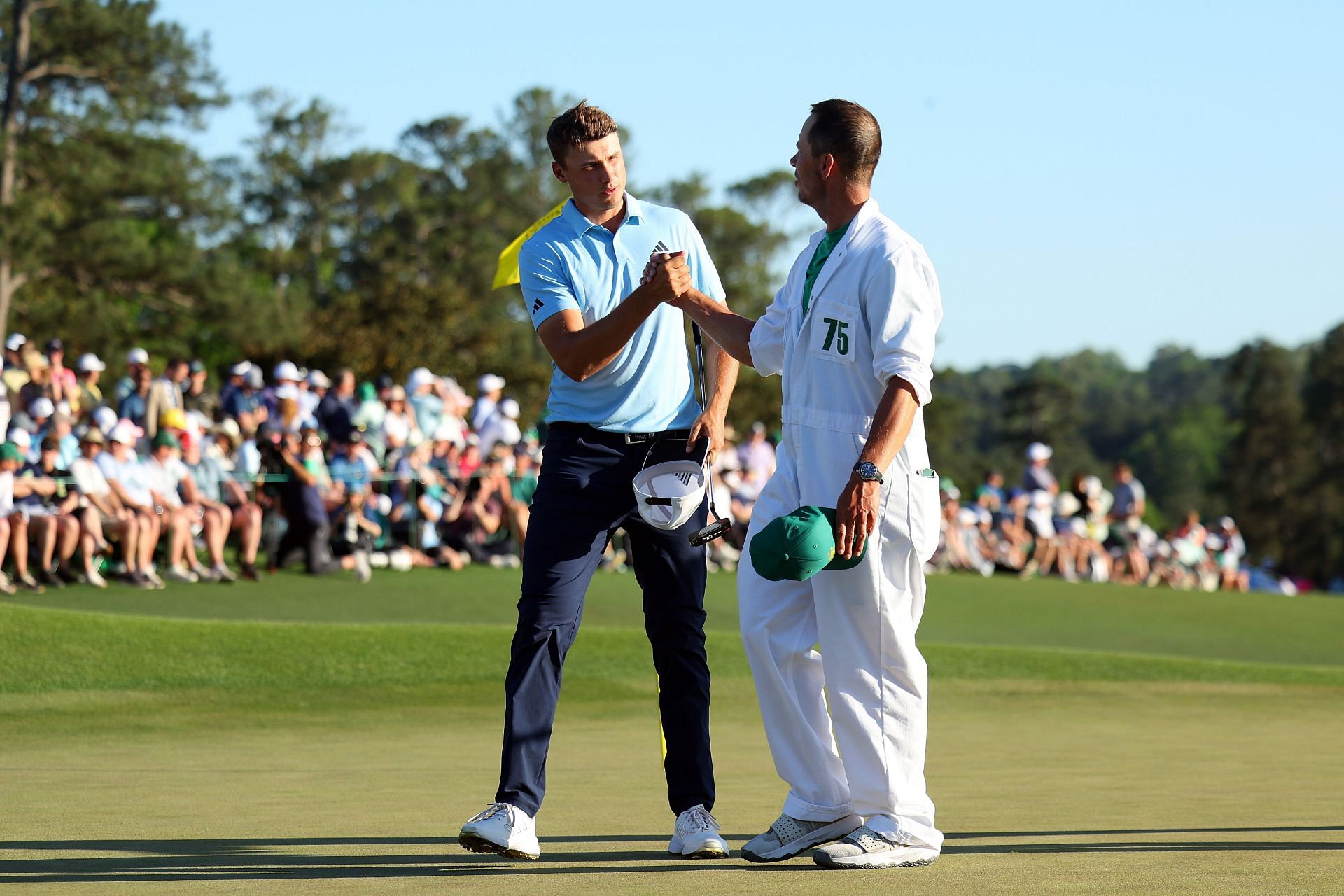 Ludvig &Aring;berg of Sweden and his caddie Joe Skovron shake hands on the 18th green after finishing their round during the third round of the 2024 Masters Tournament at Augusta National Golf Club (Photo by Andrew Redington/Getty Images)