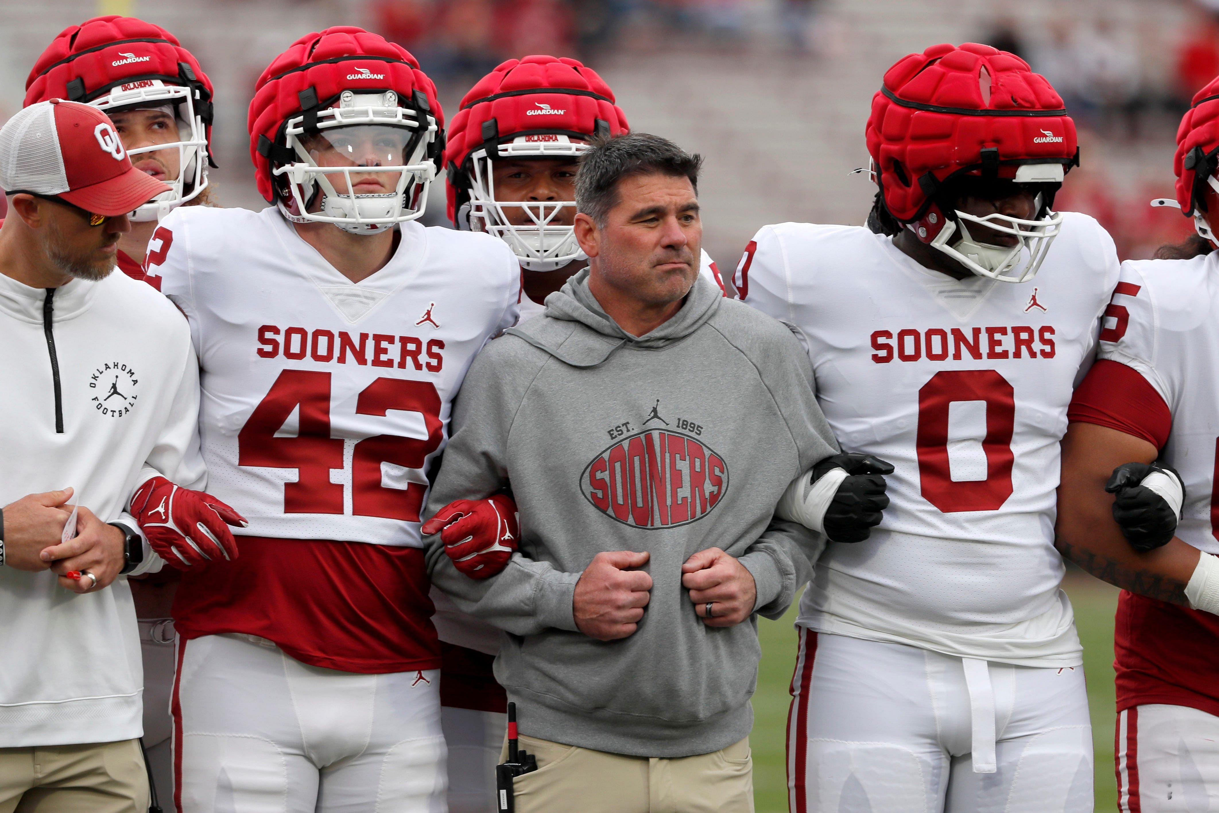 Oklahoma offensive coordinator Seth Littrell locks arms with Wyatt Gilmore (42) and David Stone (0) before a University of Oklahoma (OU) Sooners spring football game at Gaylord Family-Oklahoma Memorial Stadium.