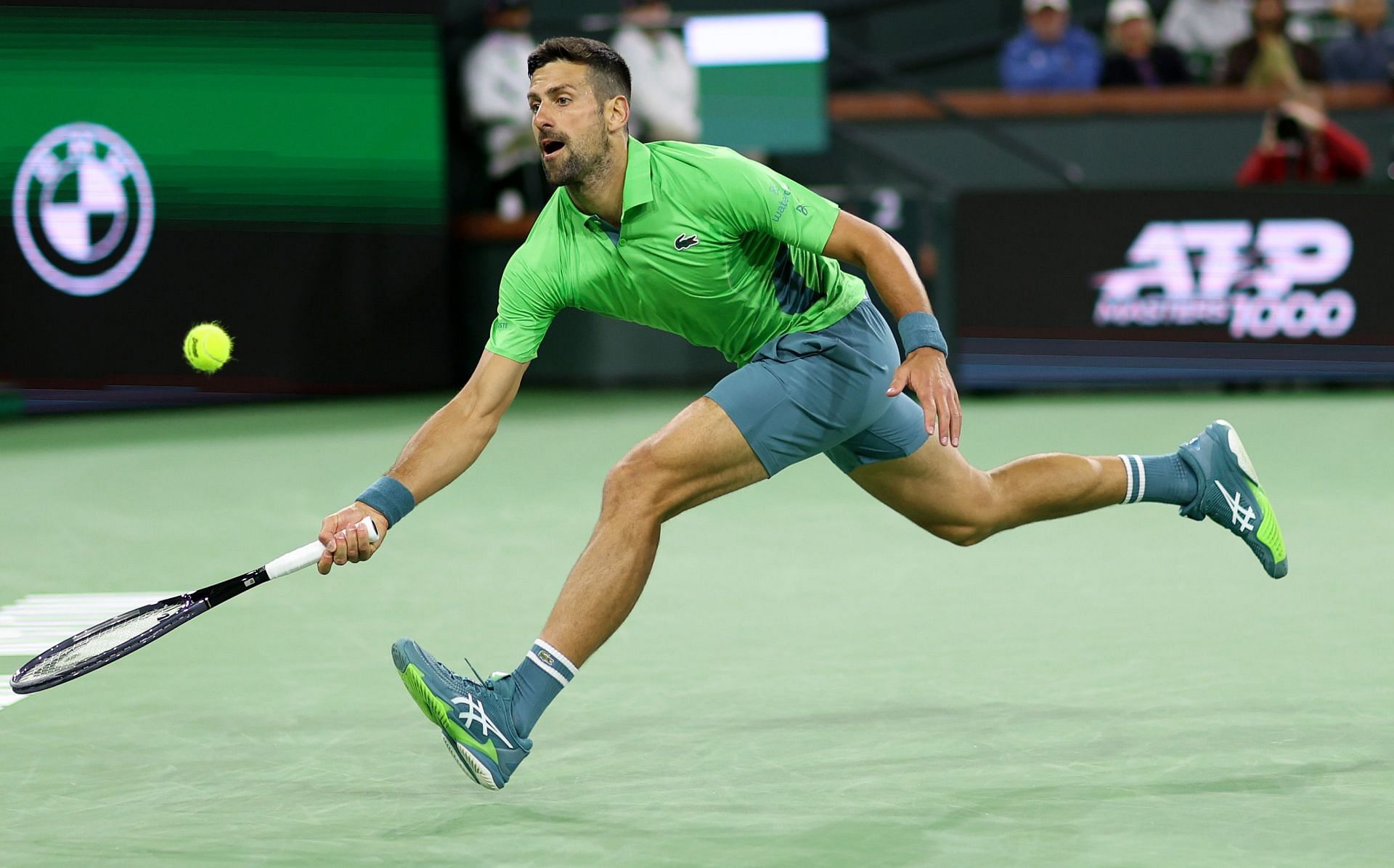 Novak Djokovic retrieves a ball at BNP Paribas Open 2024