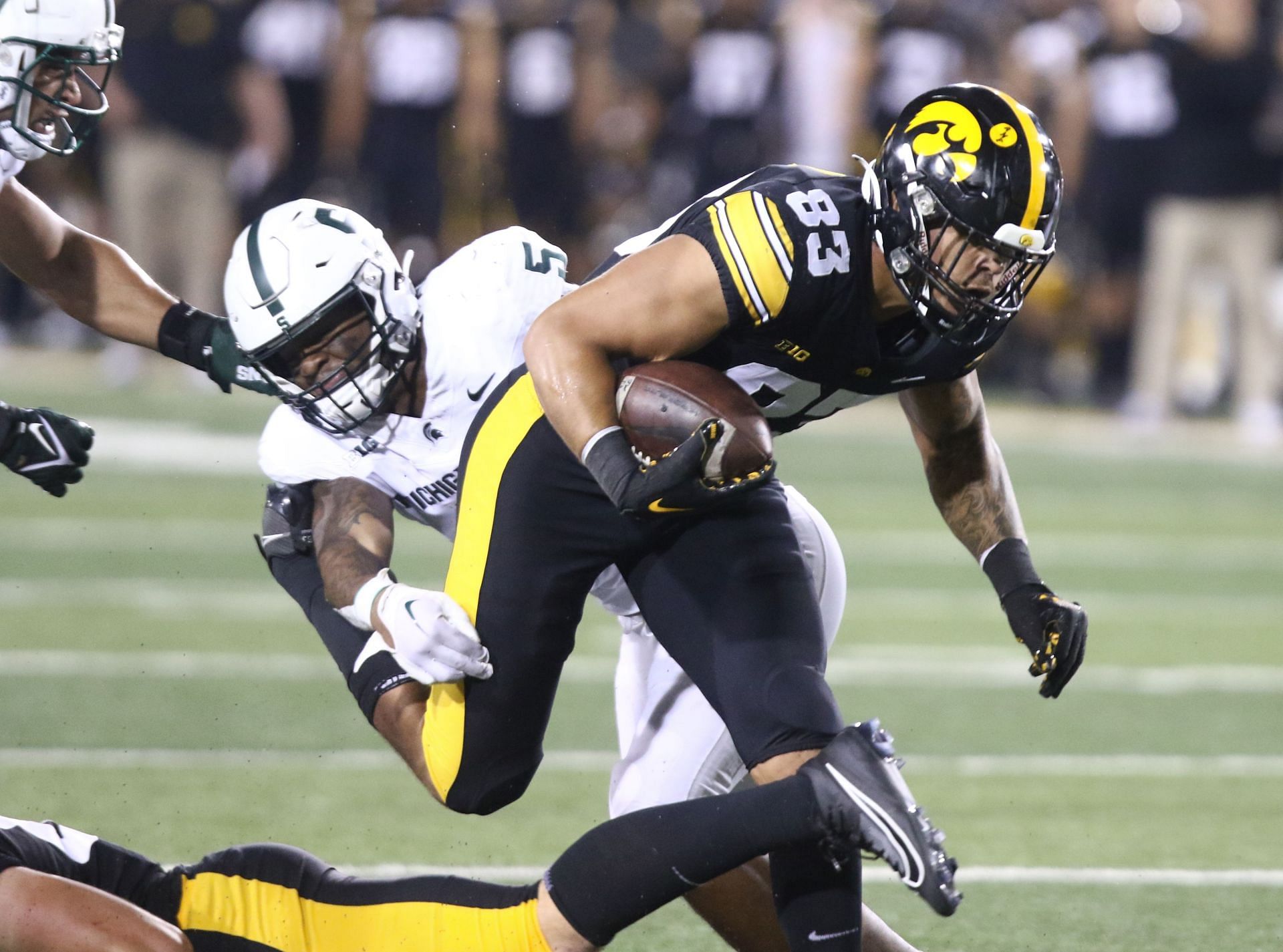 Erick All #83 of the Iowa Hawkeyes breaks a tackle on a touchdown run during the first half against linebacker Jordan Hall #5 of the Michigan State Spartans