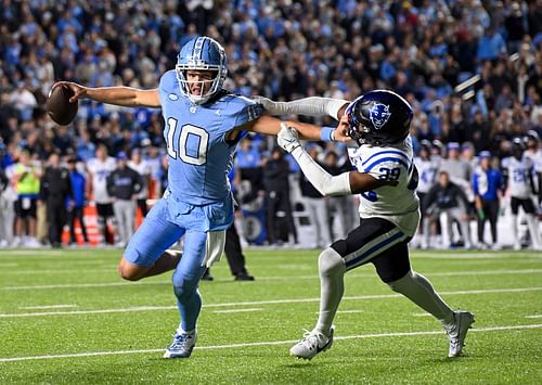 Drake Maye stiff-arming a defender