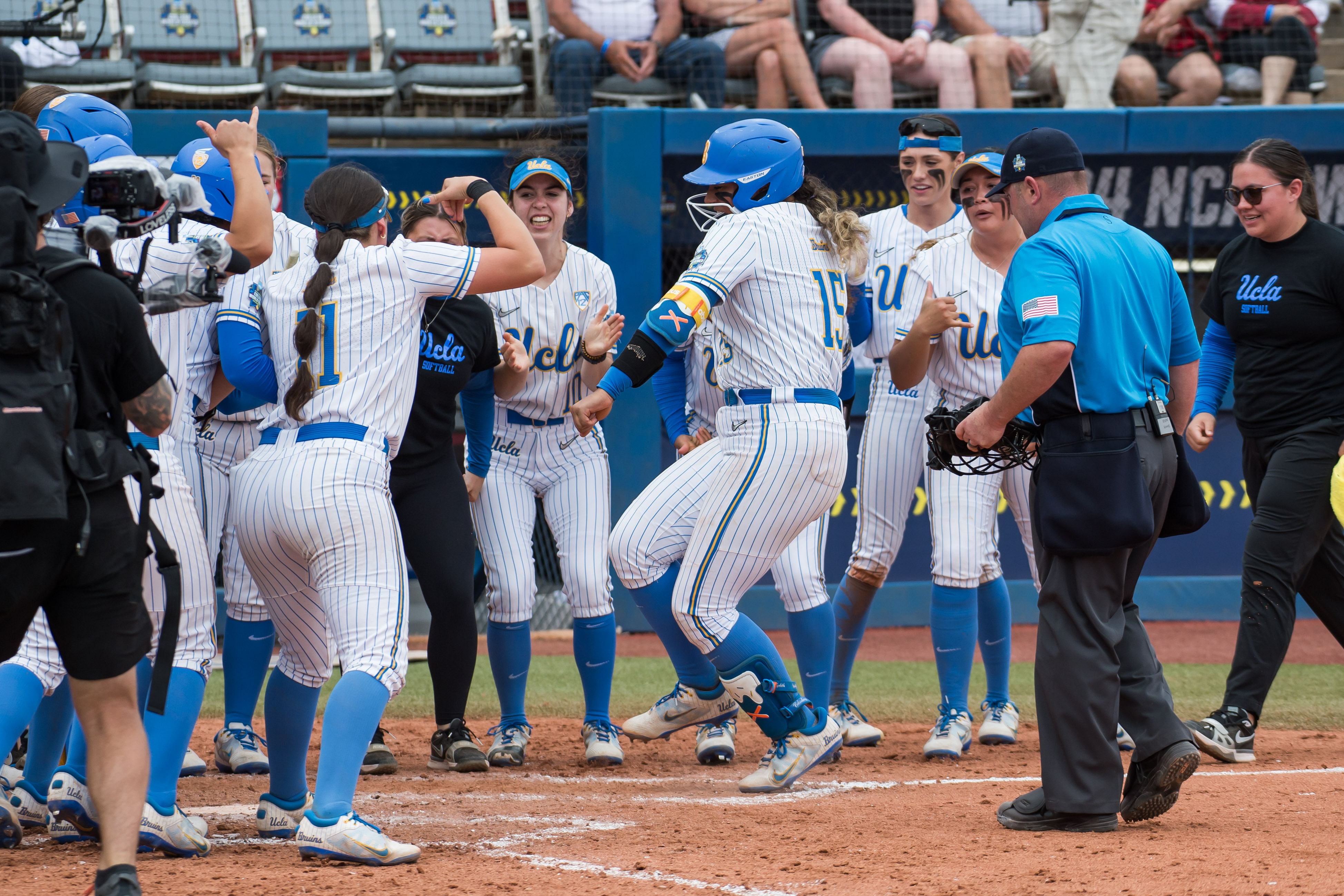 Jordan Woolery celebrates her clutch home run with her UCLA Bruins teammates during their College World Series opener.