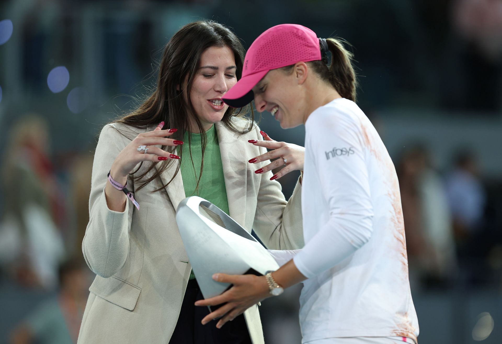 Iga Swiatek receiving the Madrid Open trophy from Garbine Muguruza.