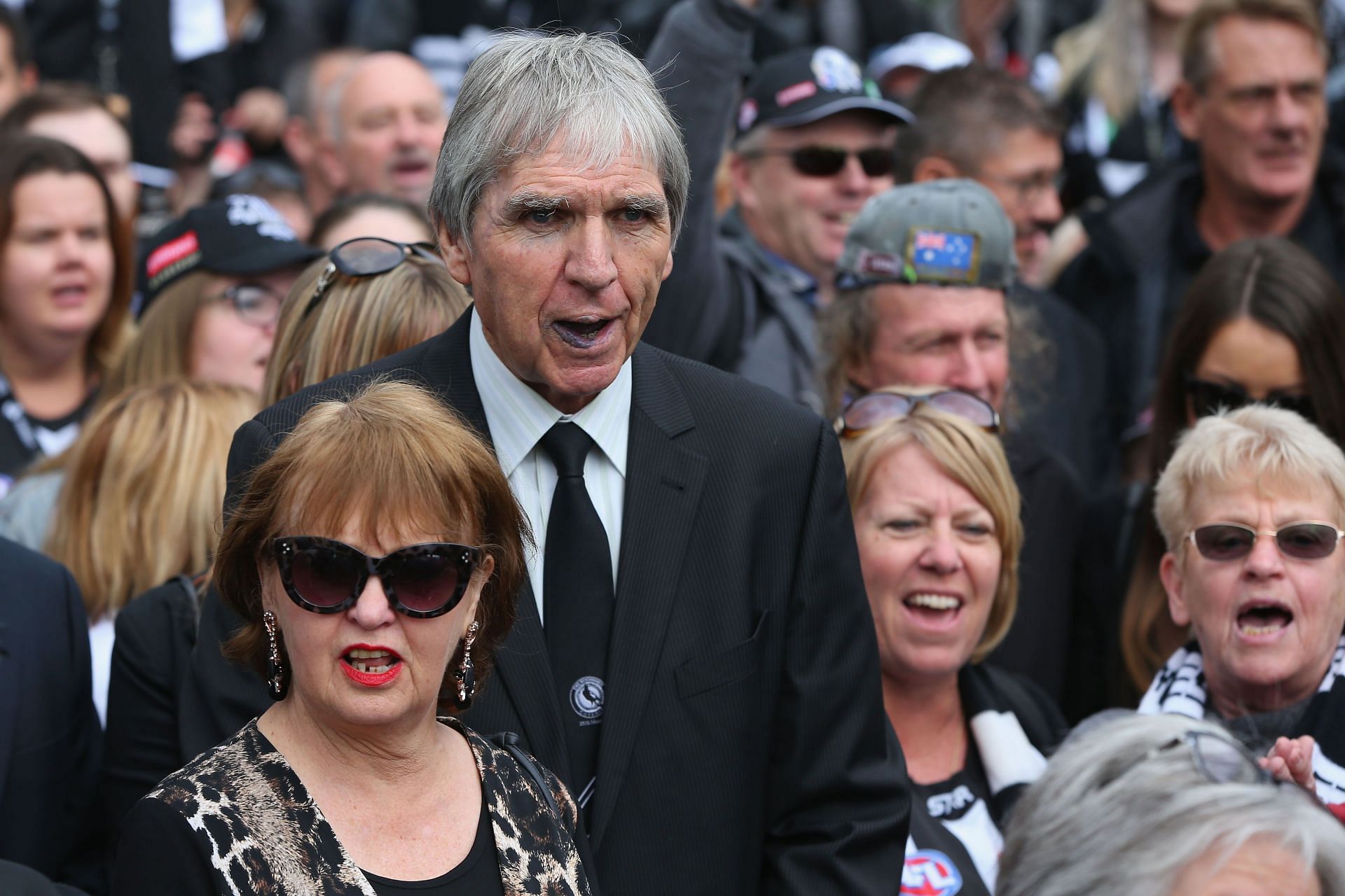 Magpies legend Peter McKenna sings the club song with Magpies fans as they march together for their 125-year celebrations