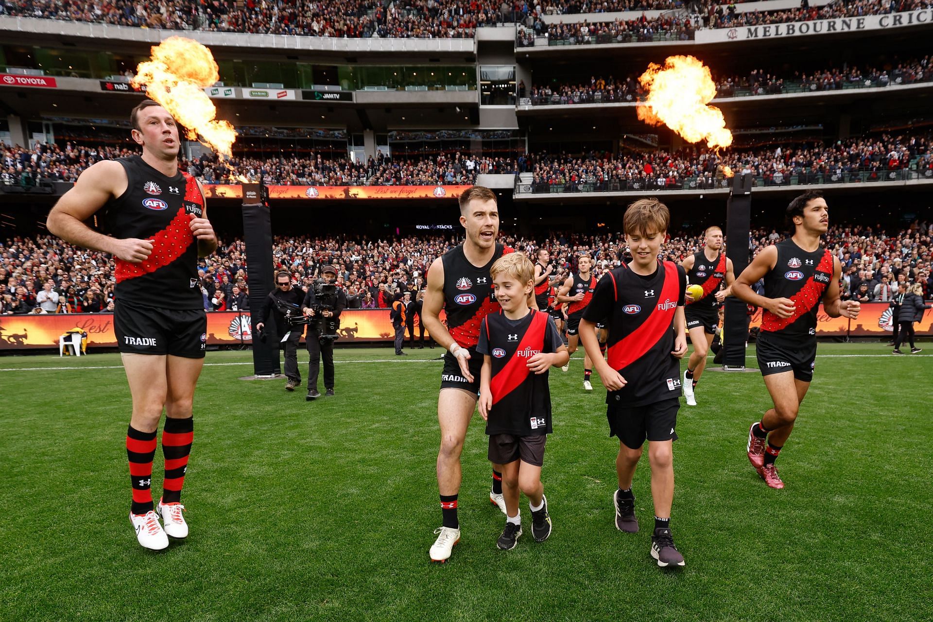 Zach Merrett of the Bombers leads his team on to the field