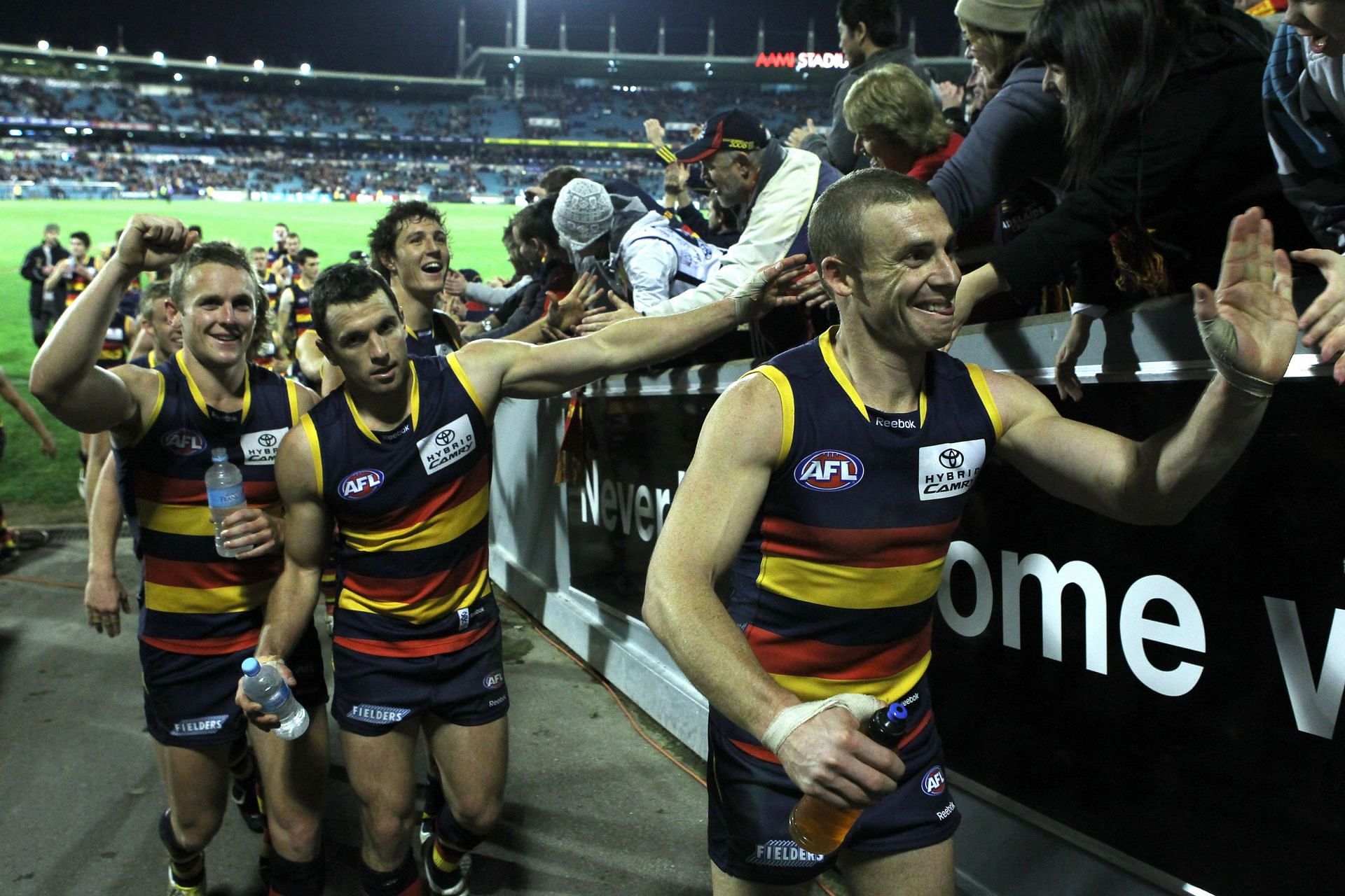 Simon Goodwin of the Crows leads the team off the field and celebrate winning the game