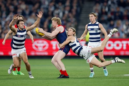 Clayton Oliver of the Demons is tackled by Mark Blicavs of the Cats.