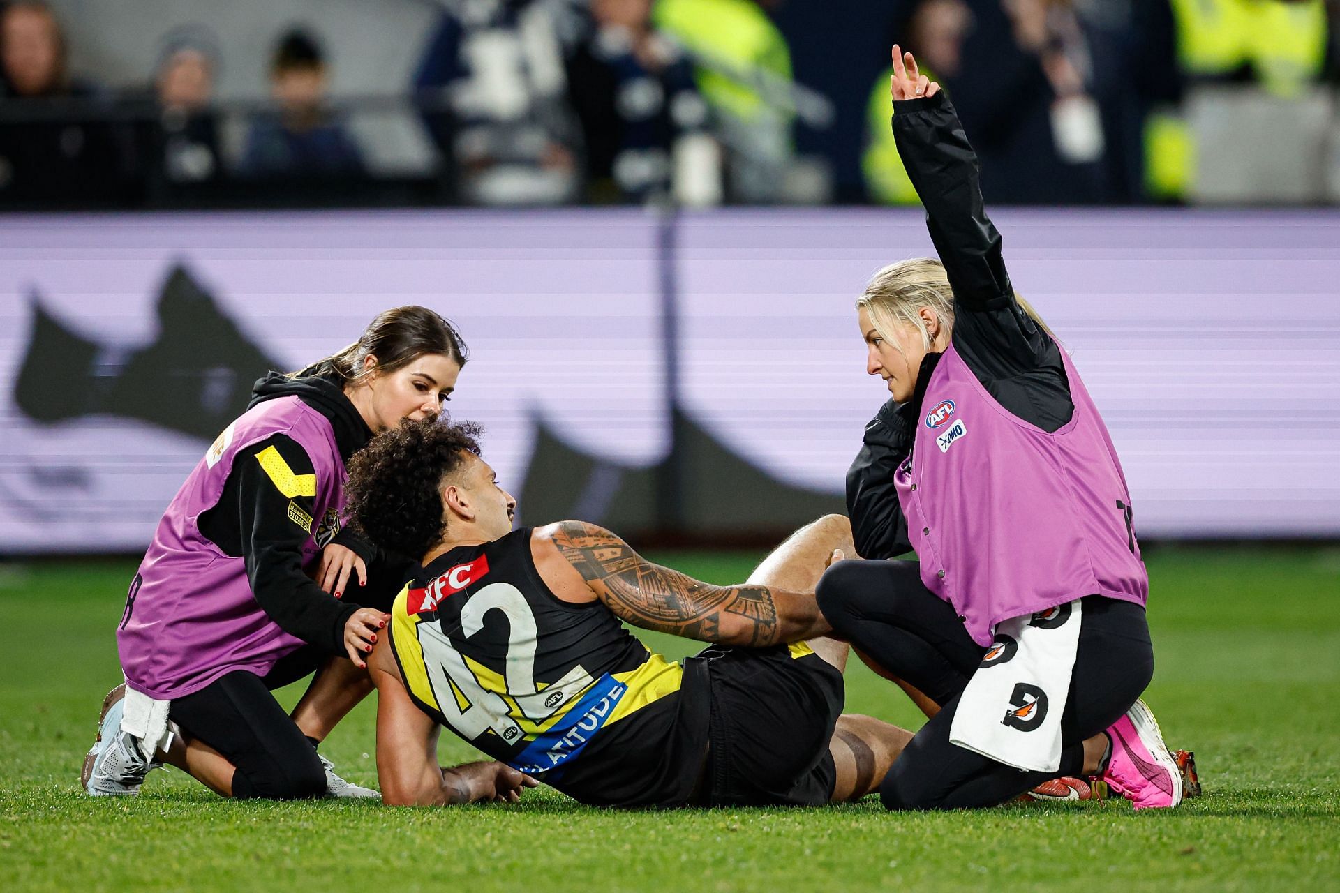 Mykelti Lefau of the Tigers is attended to by medical staff during the 2024 AFL Round 12 match between the Geelong Cats and the Richmond Tigers