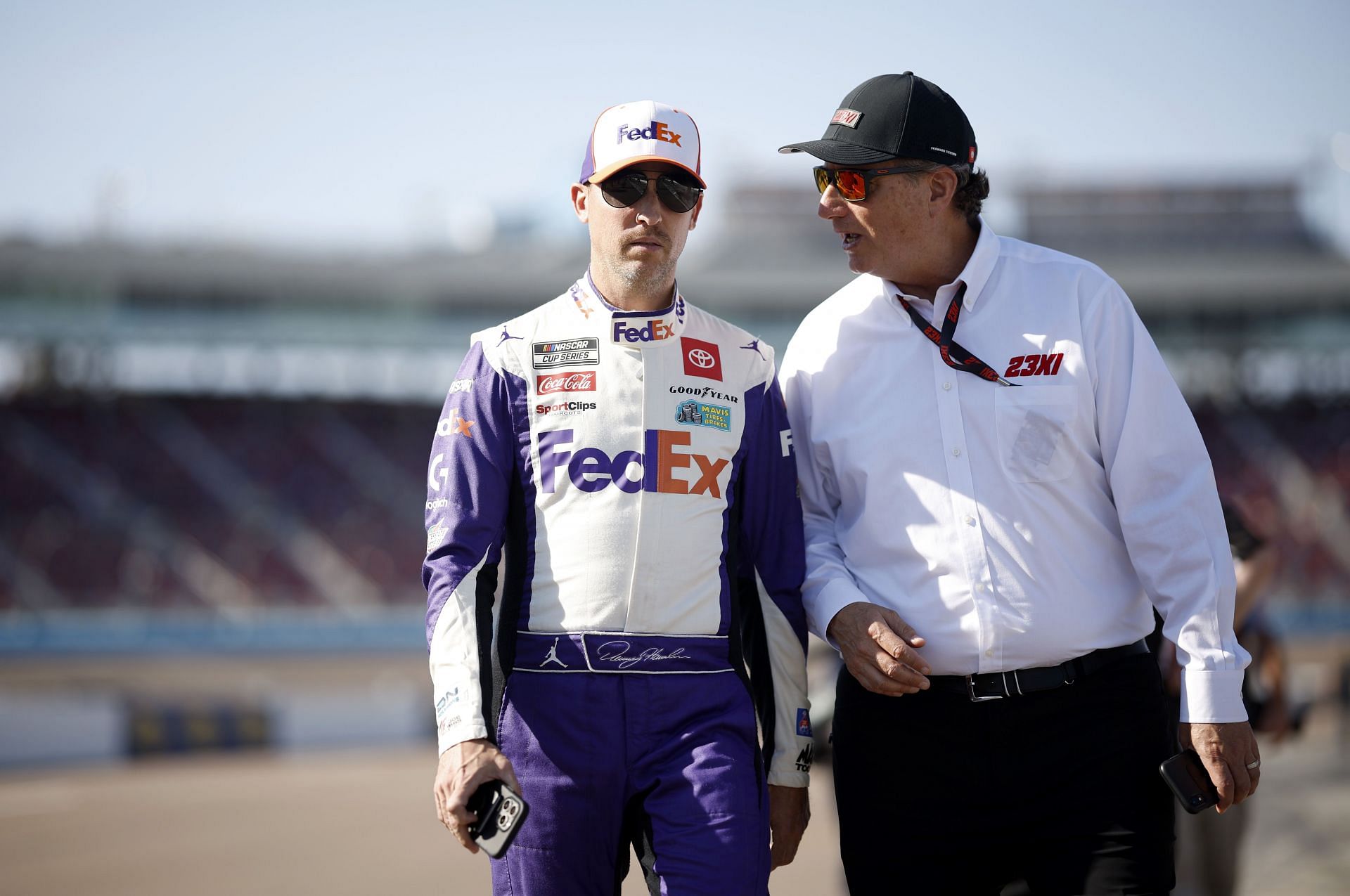 NASCAR Cup Series Championship - Qualifying AVONDALE, ARIZONA - NOVEMBER 04: Denny Hamlin, driver of the #11 FedEx Toyota, speaks with staff member of 23XI Racing on the grid during qualifying for the NASCAR Cup Series Championship at Phoenix Raceway on November 04, 2023 in Avondale, Arizona. (Photo by James Gilbert/Getty Images)