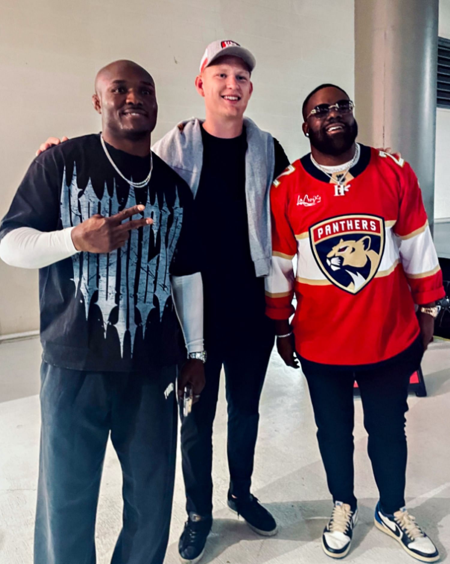 Kamaru Usman and Mark Ingram posing with Brady Tkachuk