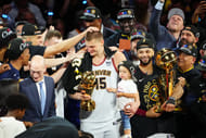 Denver Nuggets center Nikola Jokic (15) holds his daughter as he celebrates winning the Bill Russell NBA Finals MVP Award. Photo Credit: Imagn