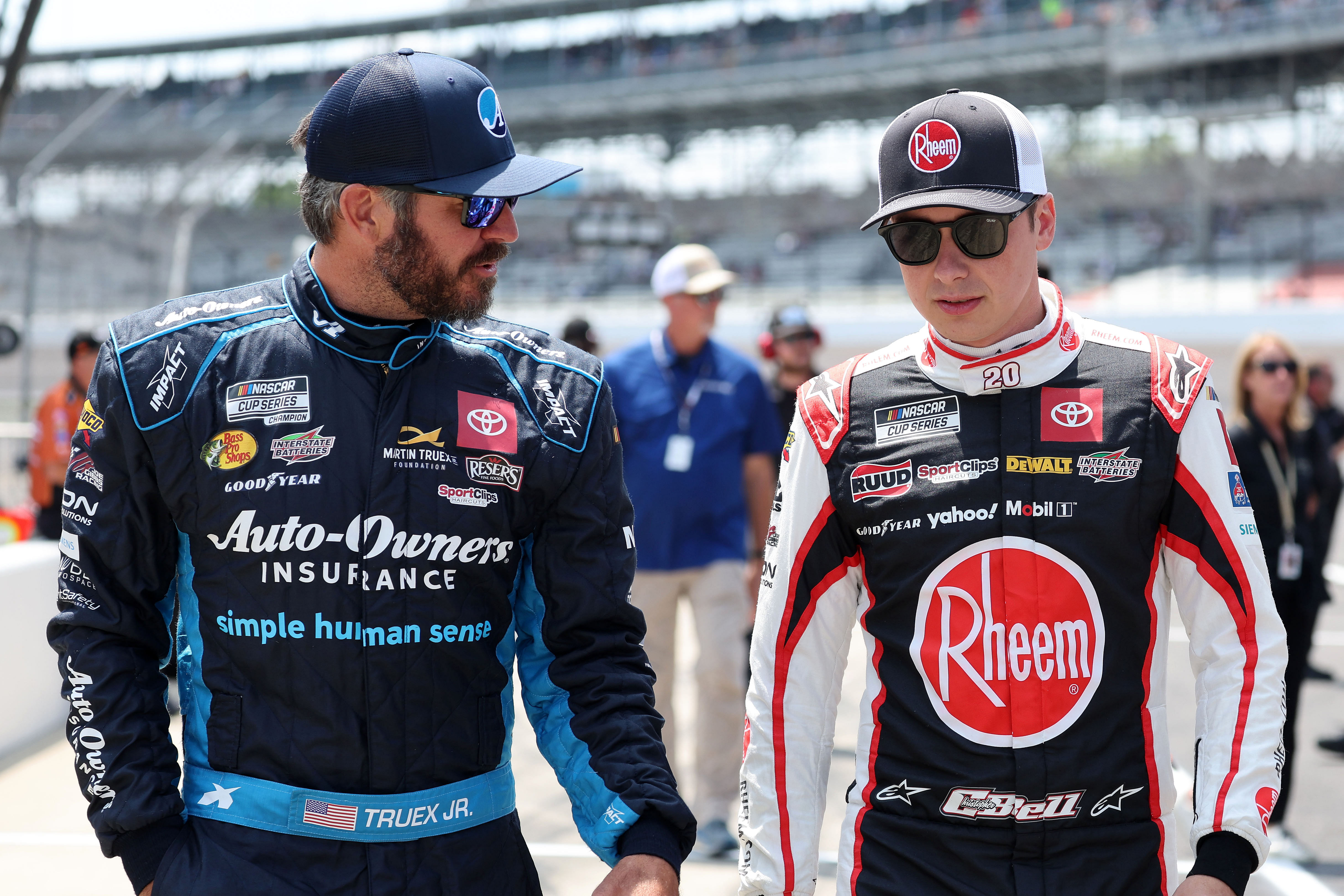 Jul 20, 2024; Indianapolis, Indiana, USA; NASCAR Cup Series driver Martin Truex Jr. (19) and driver Christopher Bell (20) talk during qualifying for the Brickyard 400 at Indianapolis Motor Speedway. Mandatory Credit: Mike Dinovo-USA TODAY Sports