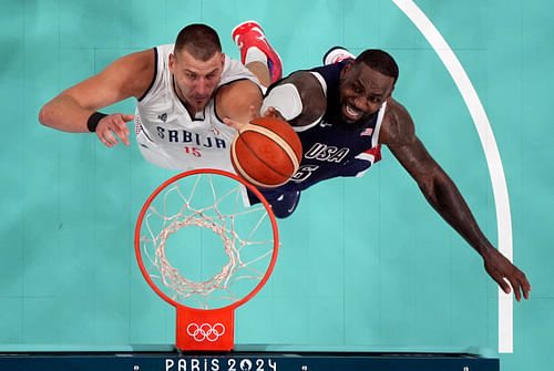 Nikola Jokic and Lebron James jump for a rebound during a game at the 2024 Paris Olympics at Stade Pierre-Mauroy (Photo Credit: Imagn)