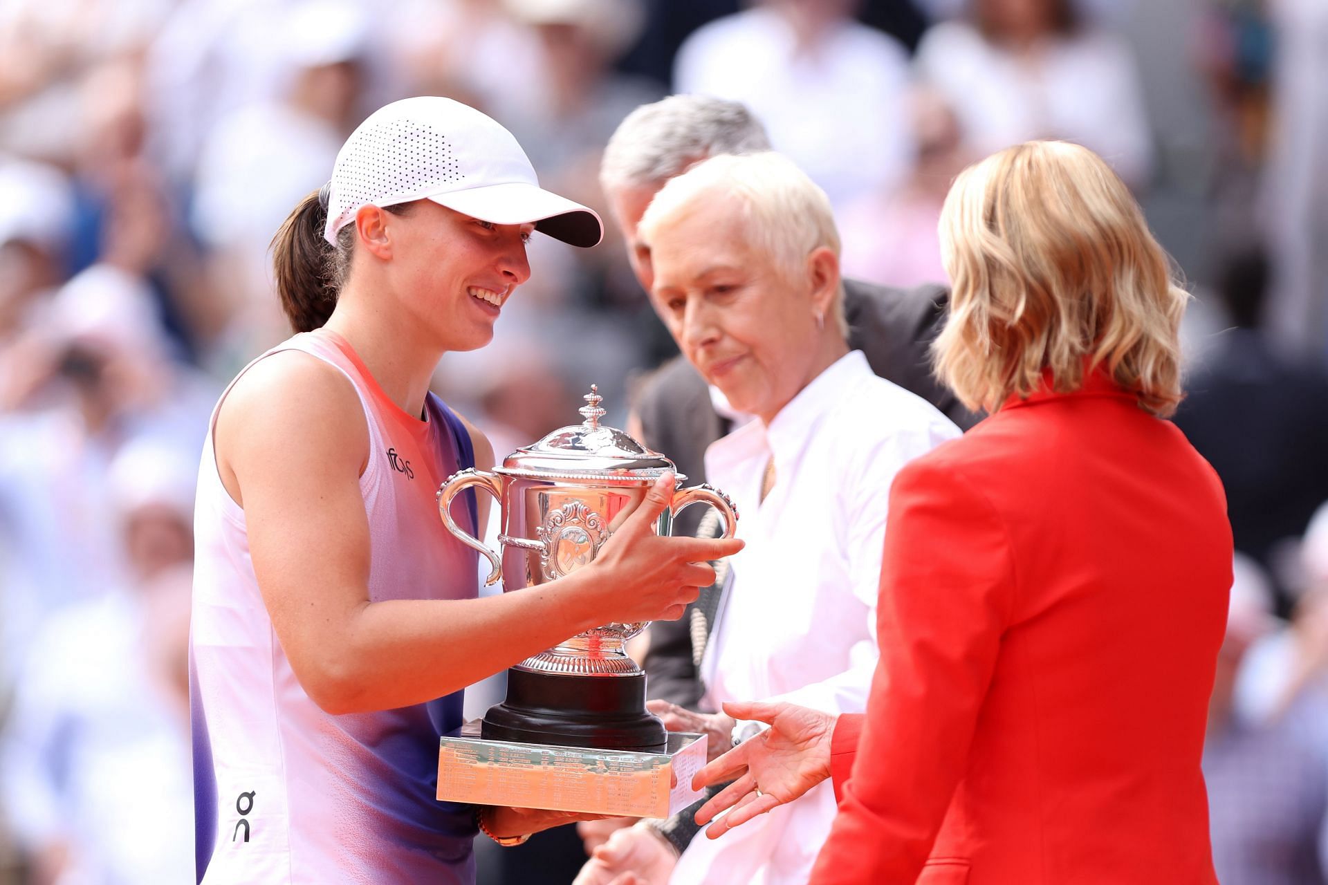 Iga Swiatek being handed the French Open trophy by Chris Evert.